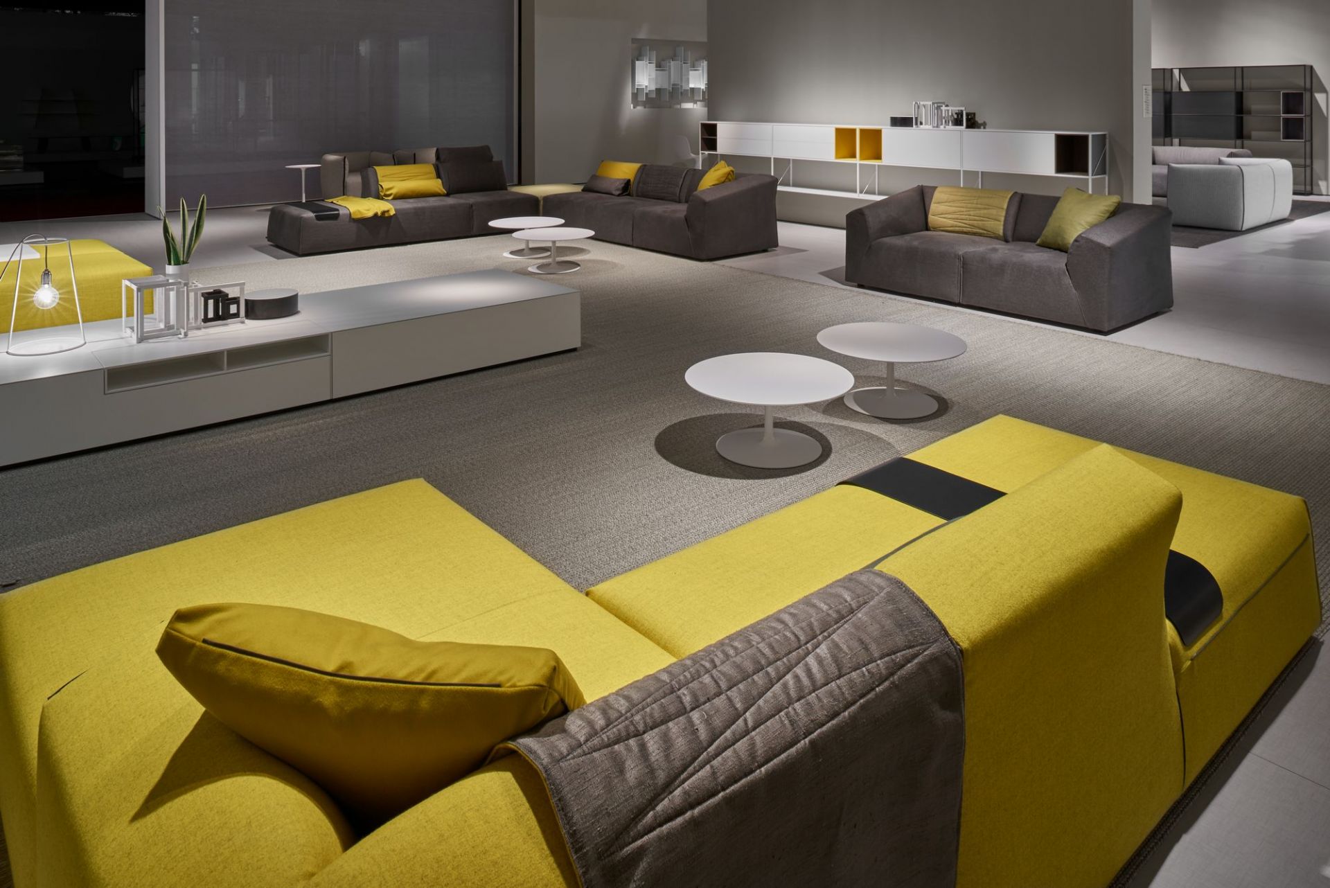 Helles Wohnzimmer mit grauen Sofas und gelbem Ecksofa, sowie weißen Flow Couchtischen von MDF Italia.