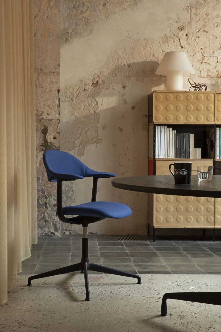 Blauer Mynt Bürodrehstuhl von Vitra mit schwarzem Fußkreuz und Armlehnen vor moderner Büroeinrichtung.