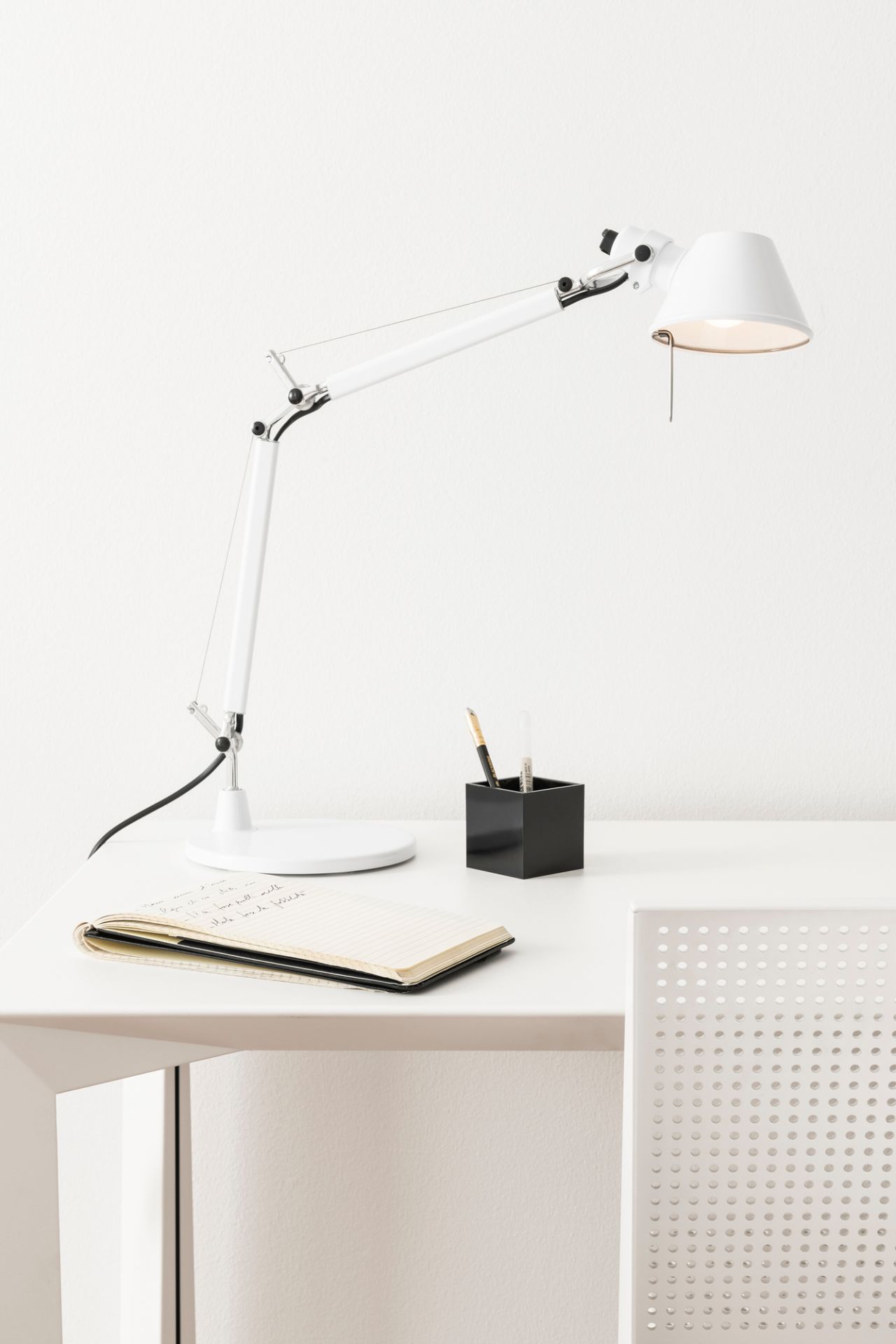 Weiße Artemide Tolomeo Micro Tischleuchte mit Fuß auf Schreibtisch mit Notizbuch und Stifthalter.