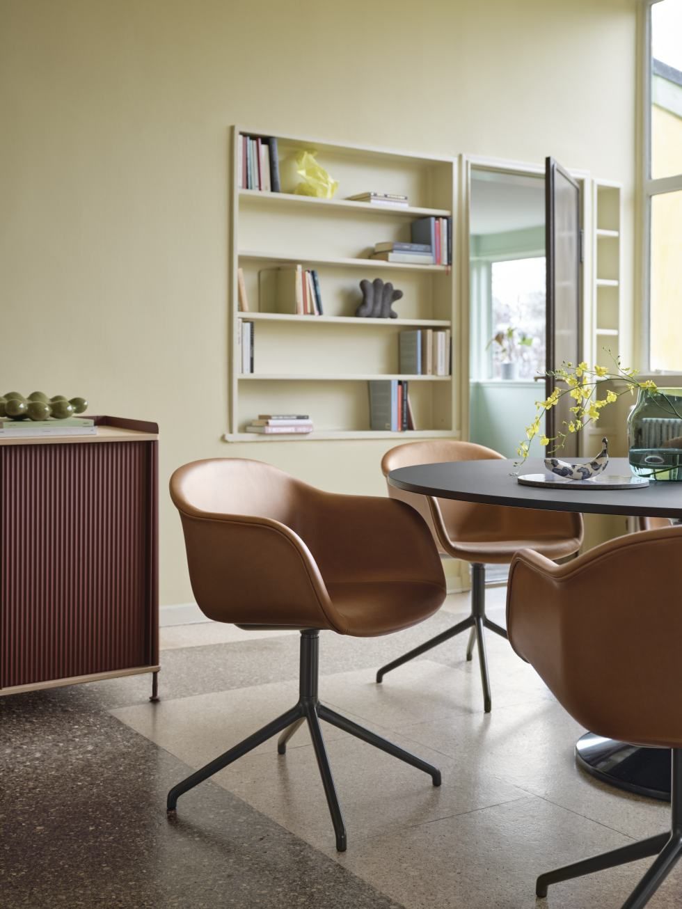 Esszimmer mit Muuto Enfold Sideboard und braunen Lederstühlen um einen runden Tisch.