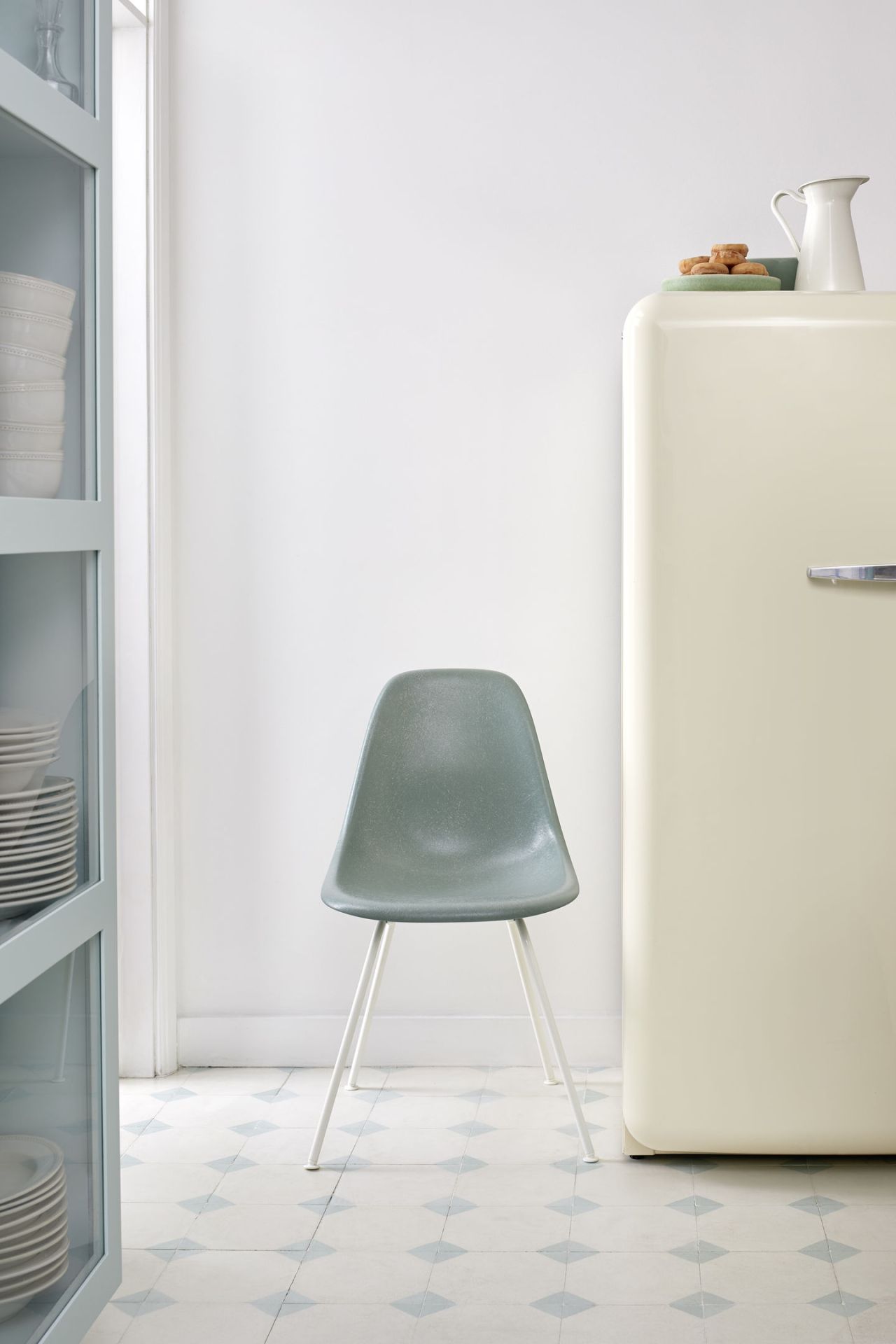 Grauer Eames Plastic Side Chair DSX Stuhl von Vitra mit weißem Gestell in minimalistischer Küchenumgebung.
