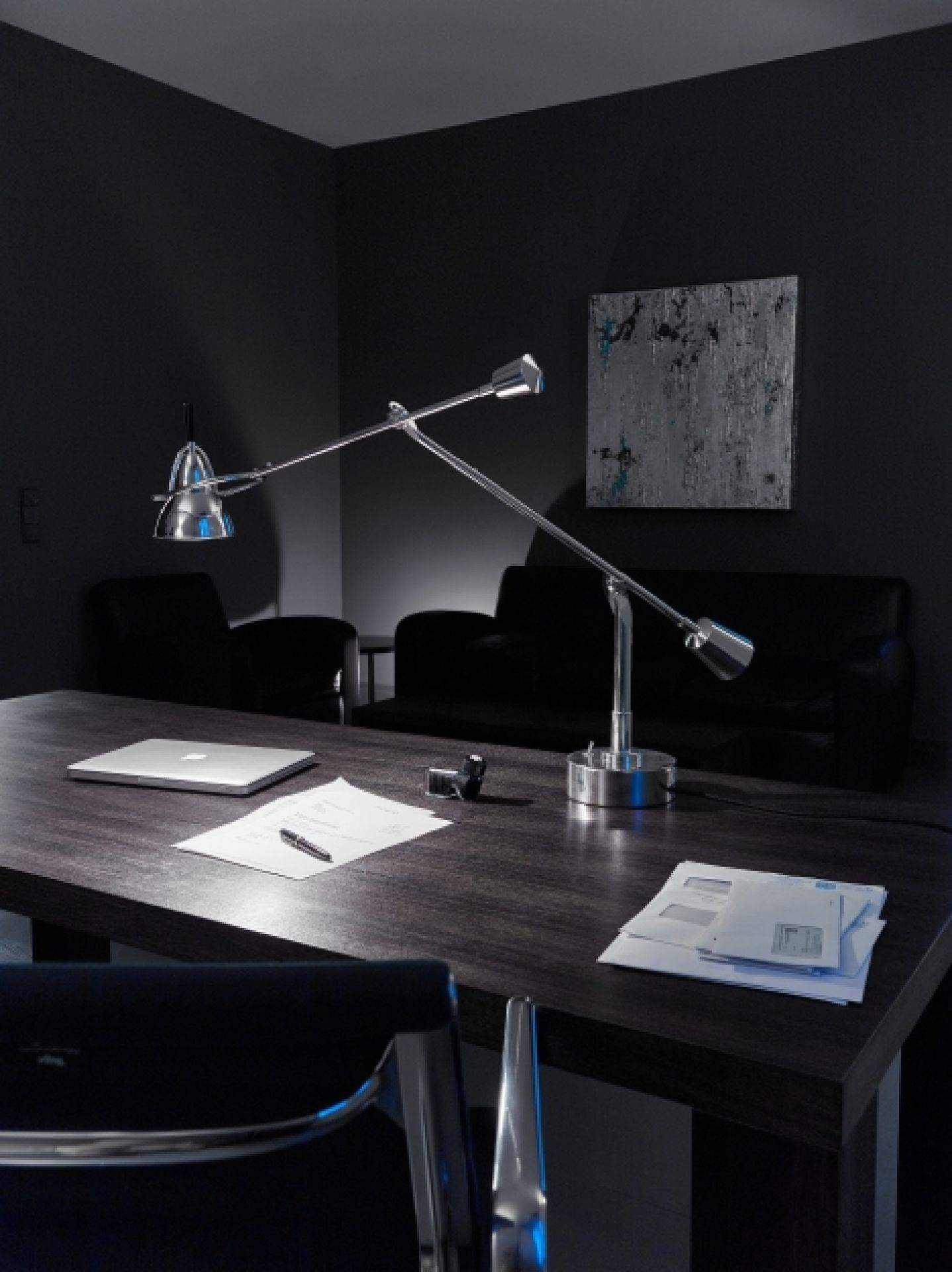 Moderne Schreibtischleuchte aus Chrom auf dunklem Holztisch mit Laptop, Papier und Stift im Büro.