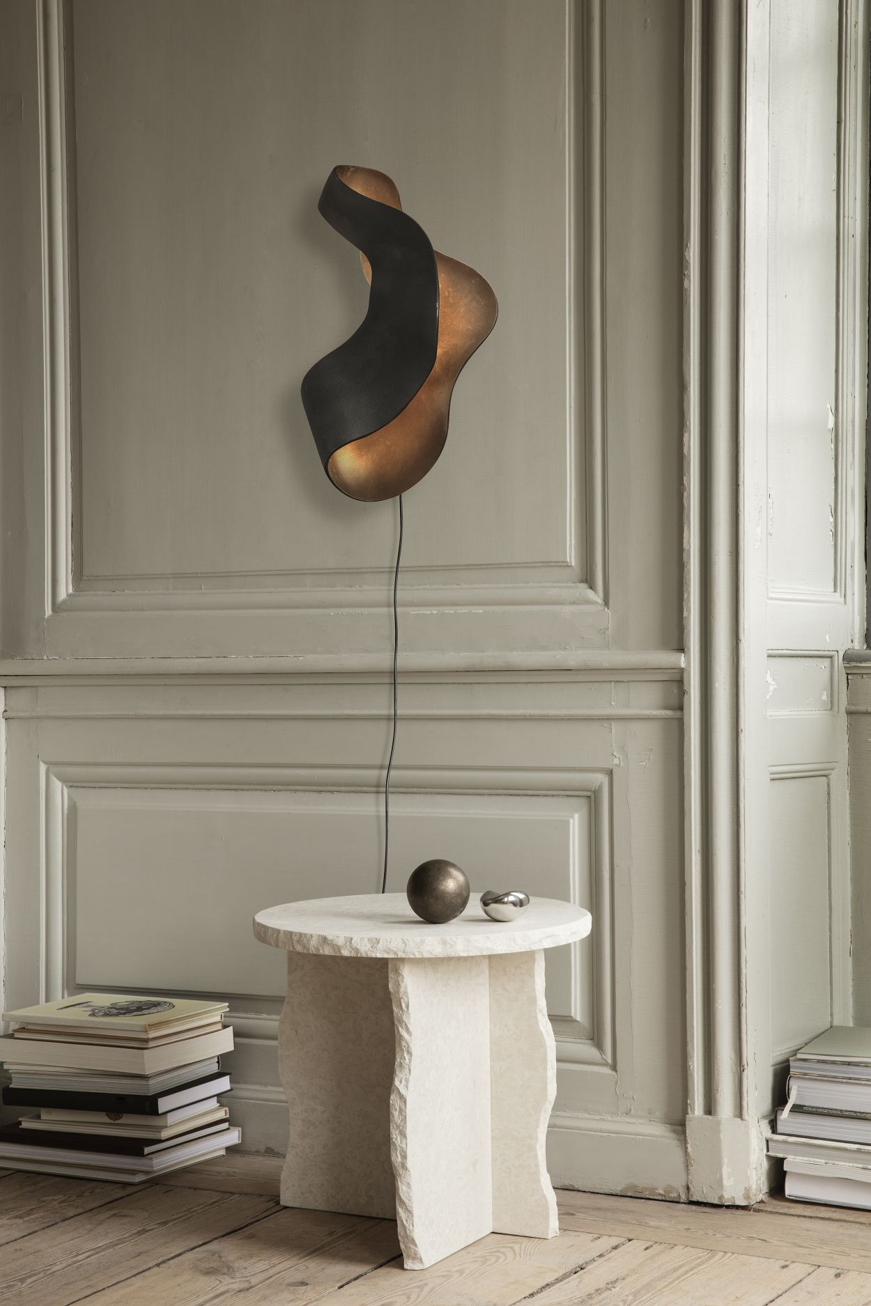 Oyster Wall Lamp Wandleuchte von Ferm Living an einer Wand, neben einem Tisch.