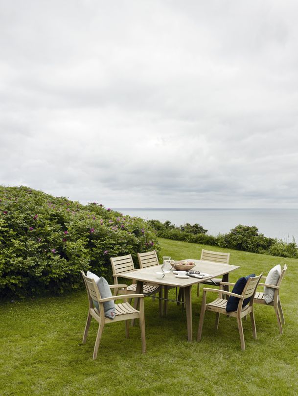 Ballare Table Tisch Outdoor von Skagerak by Fritz Hansen auf einer grünen Wiese mit Meerblick.
