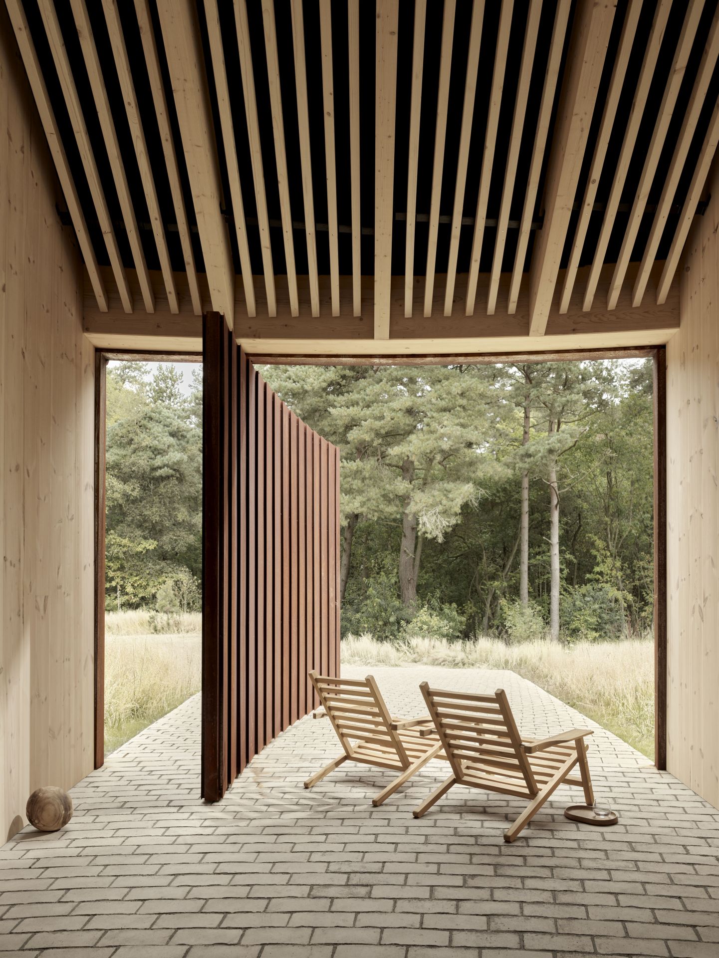 Zwei AH603 Teak Carl Hansen Sonnenstühle auf einer Terrasse mit Blick in die Natur.