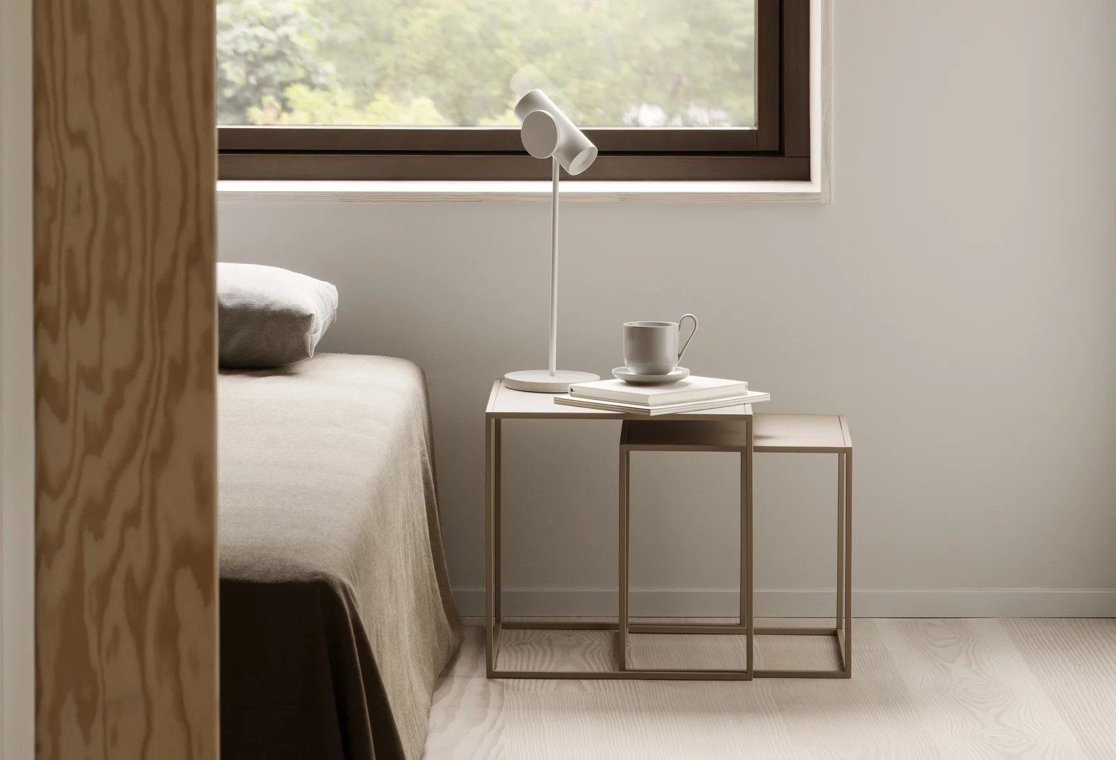 Fera Beistelltische 2er Set Blomus Stahlgrau neben einem Bett mit Lampe und Tasse.