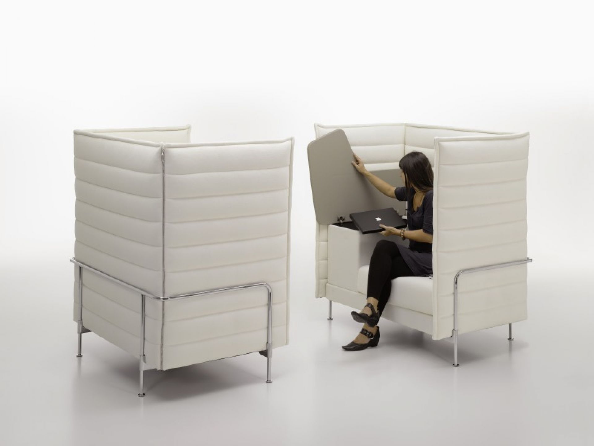 Vitra Alcove Highback Sessel: Frau öffnet Stauraum mit Laptop in weißem, modernem Bürosessel.