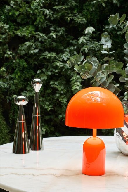 Orangefarbene Bell Portable LED Tischleuchte von Tom Dixon auf einem Tisch.
