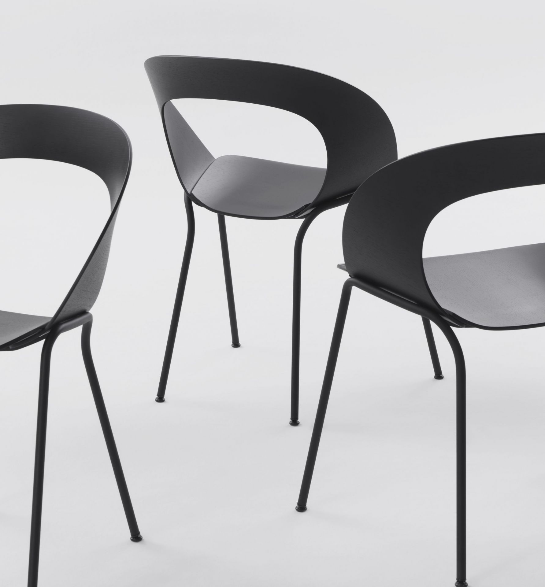 Drei schwarze Mudra Stühle von Brunner mit minimalistischem Design und filigranen Stahlbeinen auf weißem Hintergrund.