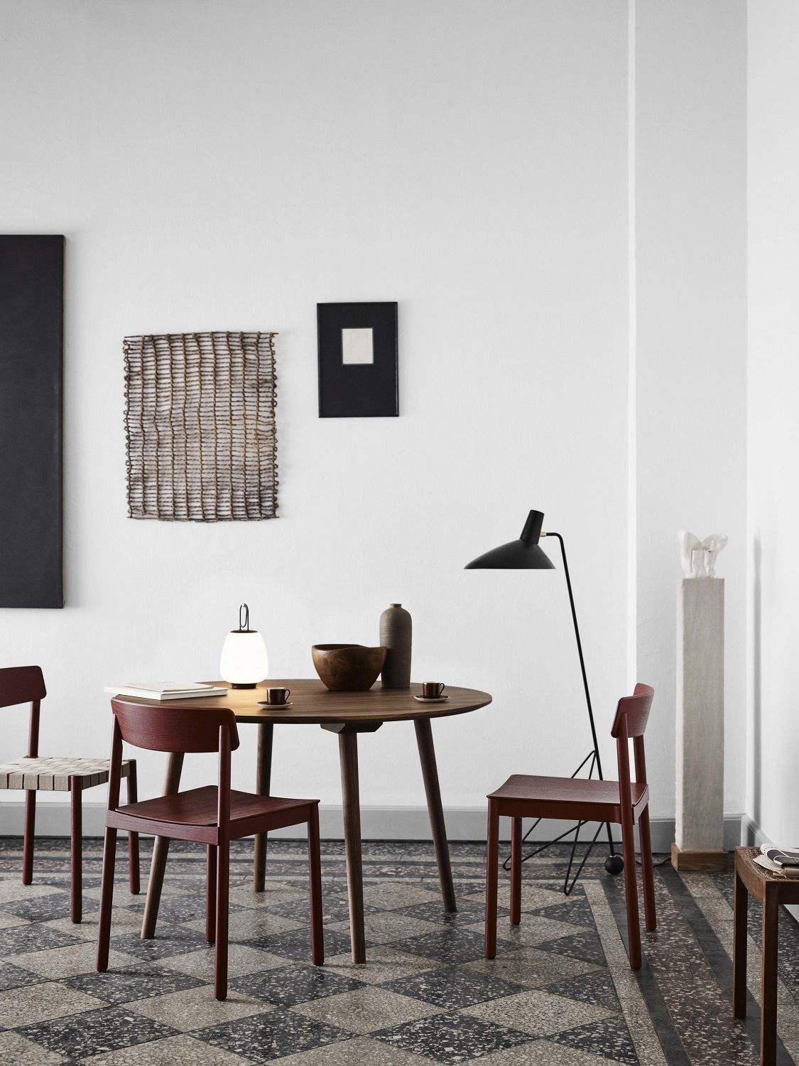 AndTradition Betty TK1 Stuhl in Burgunderrot um einen Esstisch in einem stilvollen Interieur.