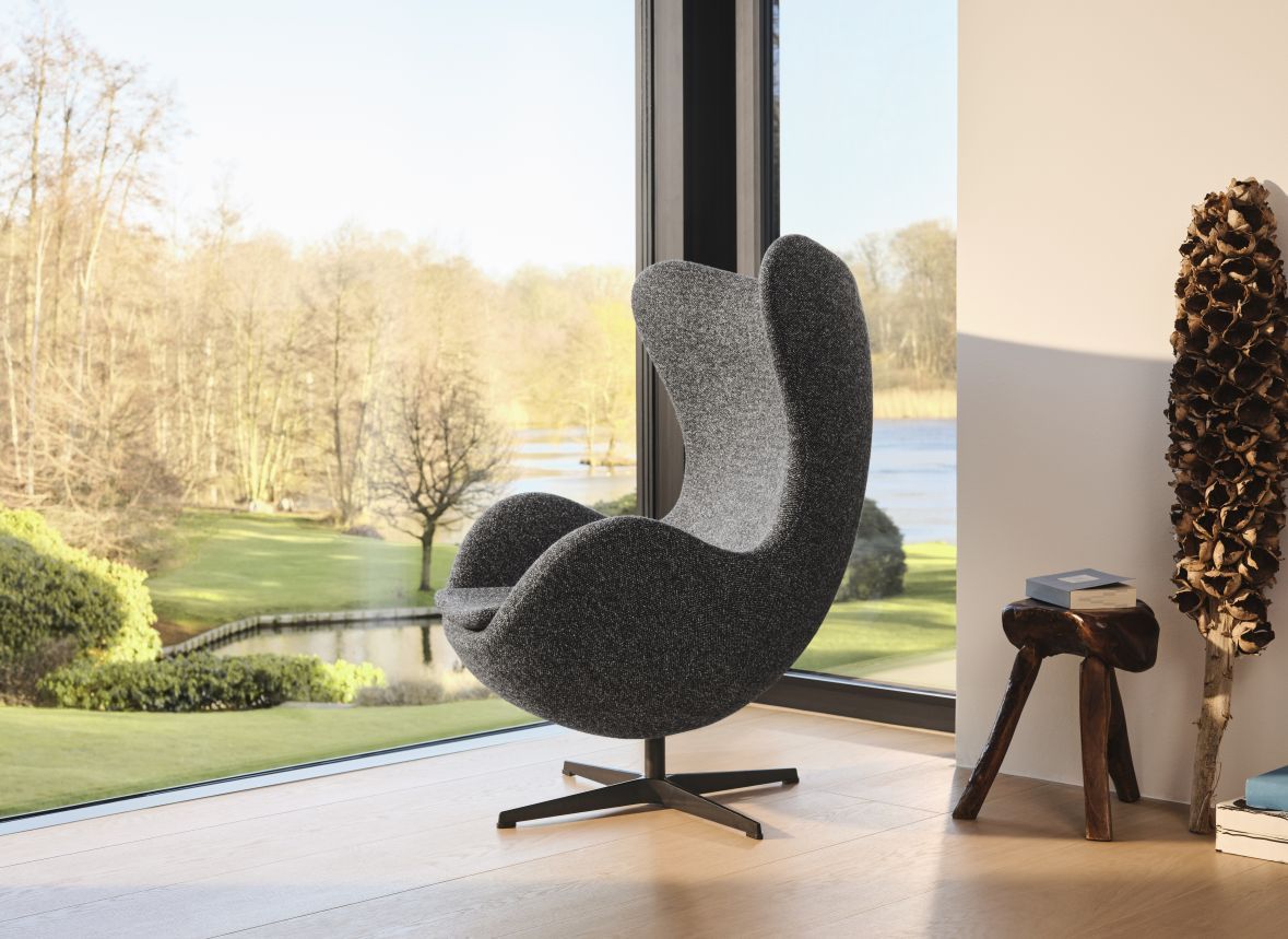 Grauer Egg Chair Sessel von Fritz Hansen vor Fenster mit Blick ins Grüne.