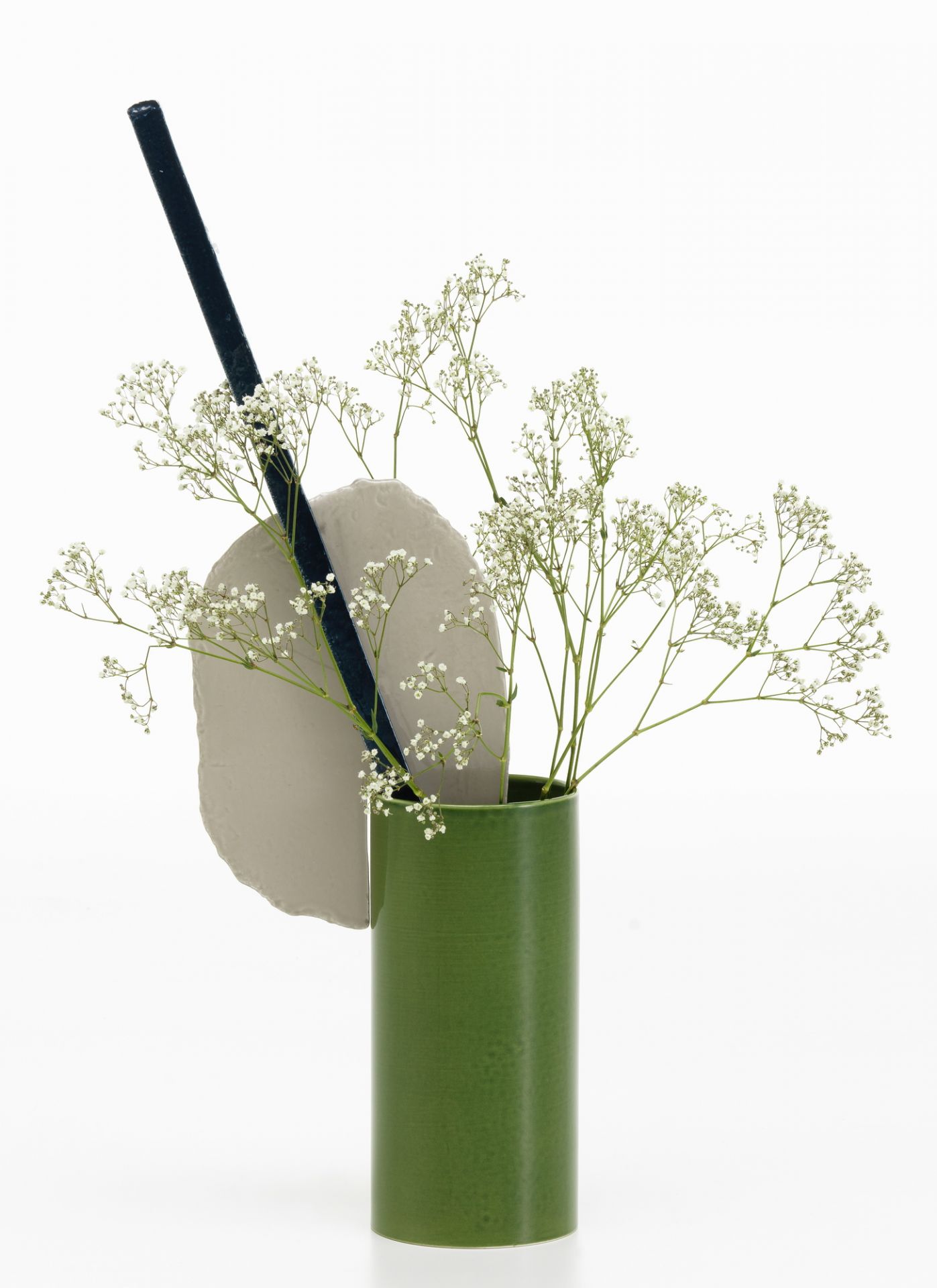 Vitra Découpage Vase: Grüne Design-Vase mit Trockenblumen, Stein-Element und schwarzem Stab auf weißem Hintergrund.