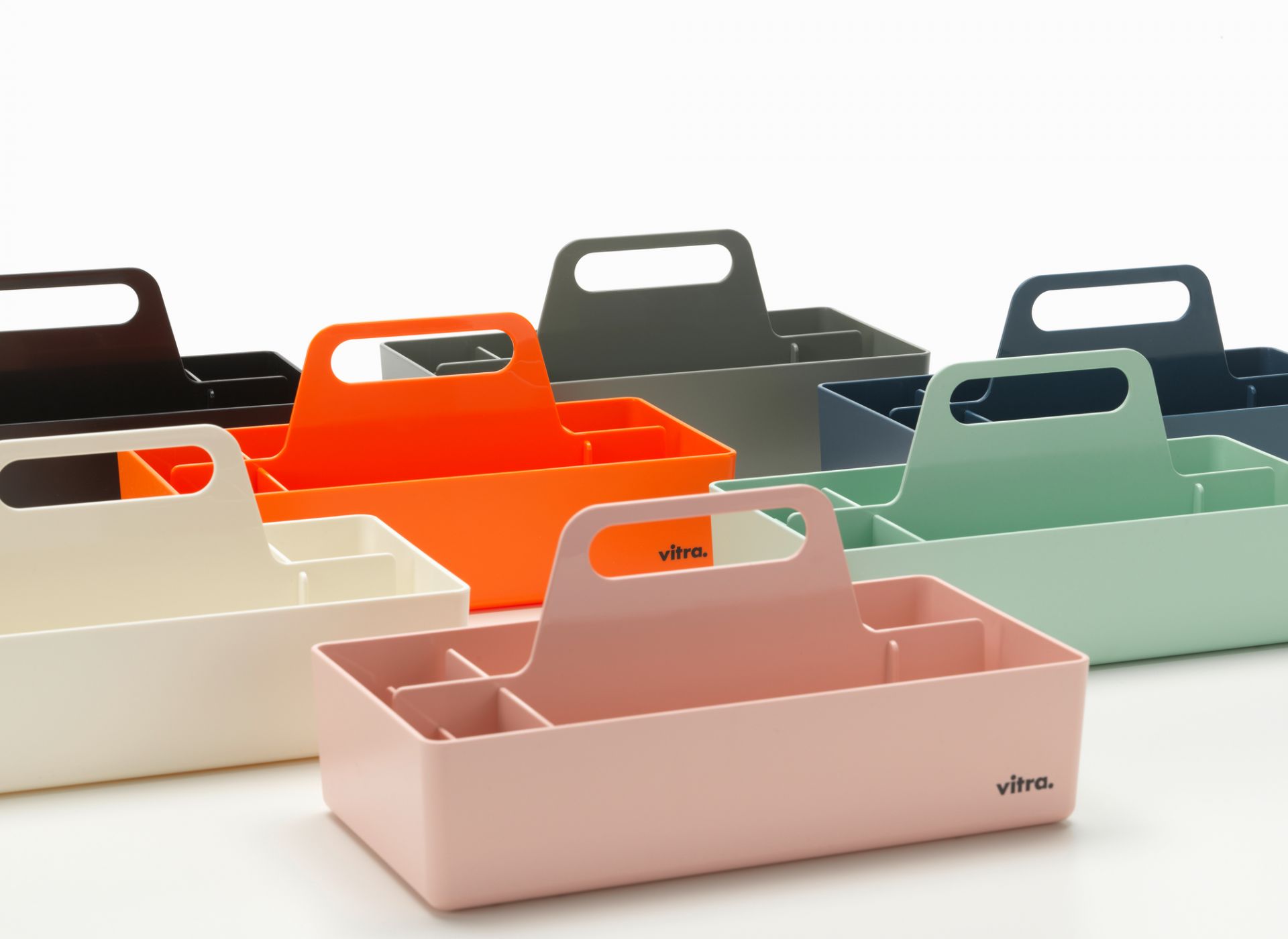 Mehrere Vitra Toolbox Organisationsboxen in verschiedenen Farben, darunter eine weiße, für Bürobedarf und Werkzeug.