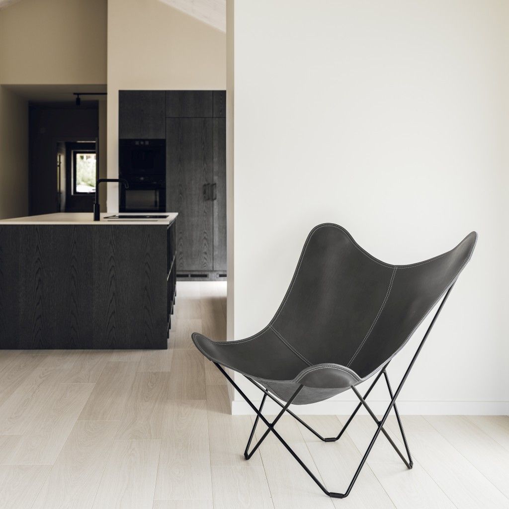 Grauer Pampa Mariposa Butterfly Chair Ledersessel mit schwarzem Metallgestell in modernem Wohnraum.