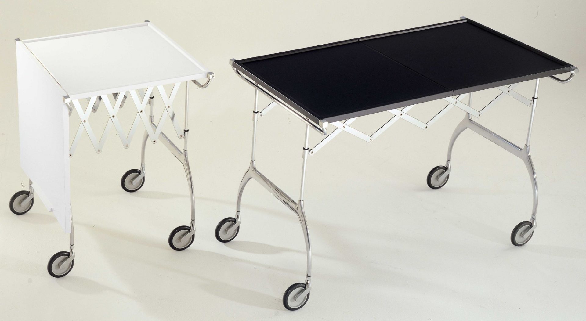 Schwarzer Kartell Battista Rollwagen neben weißem Modell, ausklappbarer Servierwagen mit Rollen.