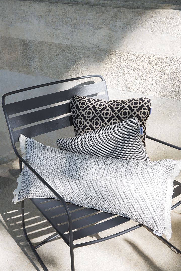 Grauer Fermob Sessel für den Außenbereich mit Kissen in Schwarz-Weiß für Garten und Terrasse.