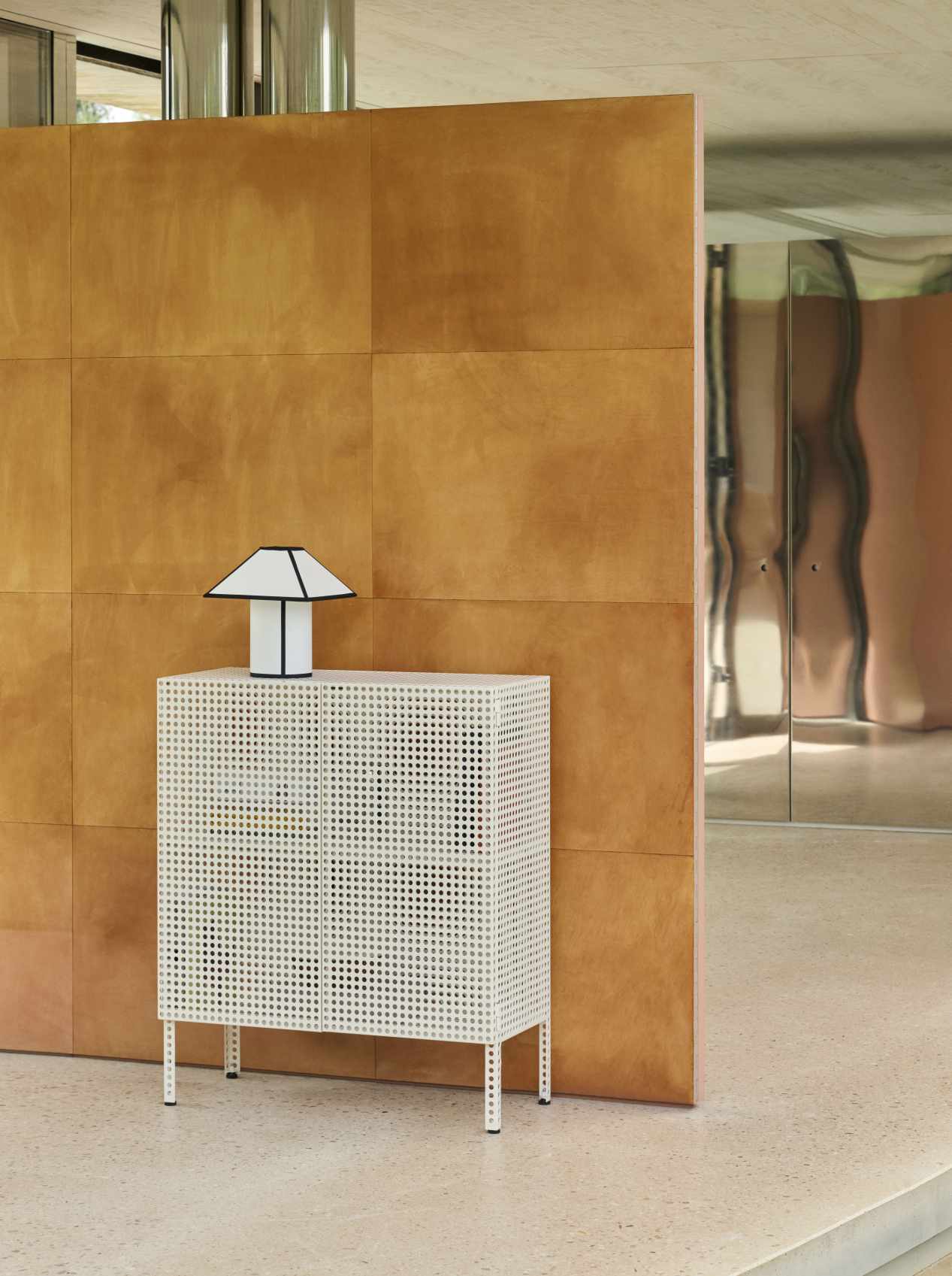 Weißes Hay Sideboard "Perforated Cabinet Floor Medium" mit Lochmuster und Lampe im modernen Interieur.