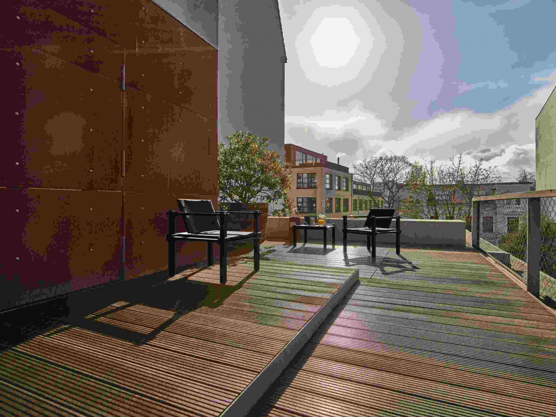 Zwei Farmer Sessel Outdoor Cor auf einer modernen Terrasse mit Holzboden und Blick auf die Stadt.