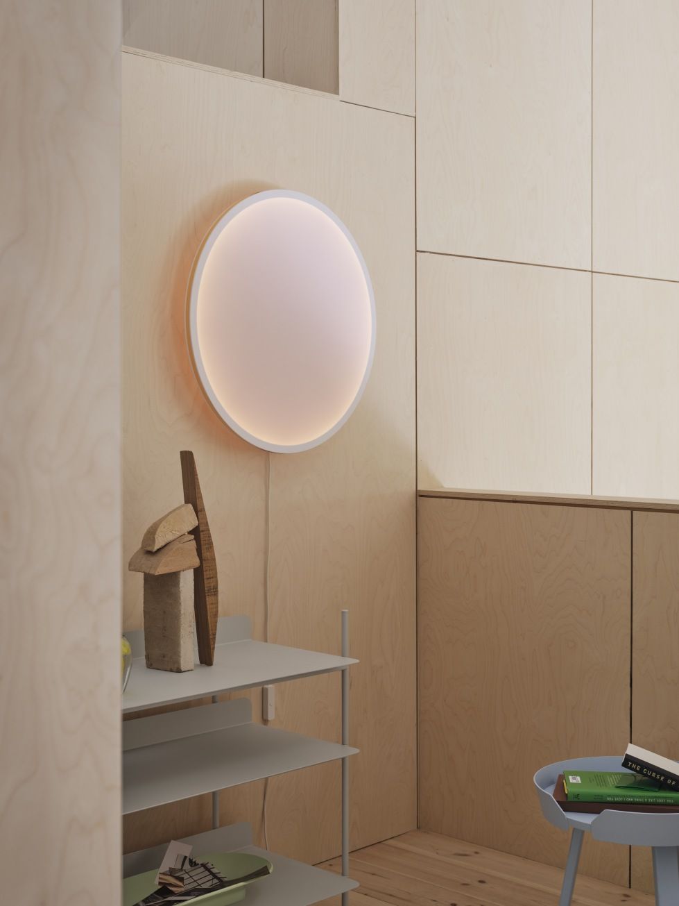 Helle, runde Muuto Wandleuchte "Calm Wall Lamp" an einer Holzwand, modernes Design.