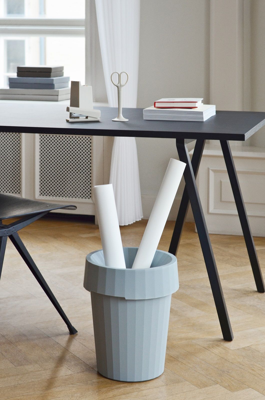 Hay Loop Stand Table mit Büromaterialien und Papierkorb im minimalistischen Design. Esstisch und Schreibtisch.