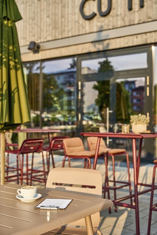 Vapio Barstool Barhocker Outdoor Weishäupl vor Restaurant, Kaffeetasse und Speisekarte auf Tisch.