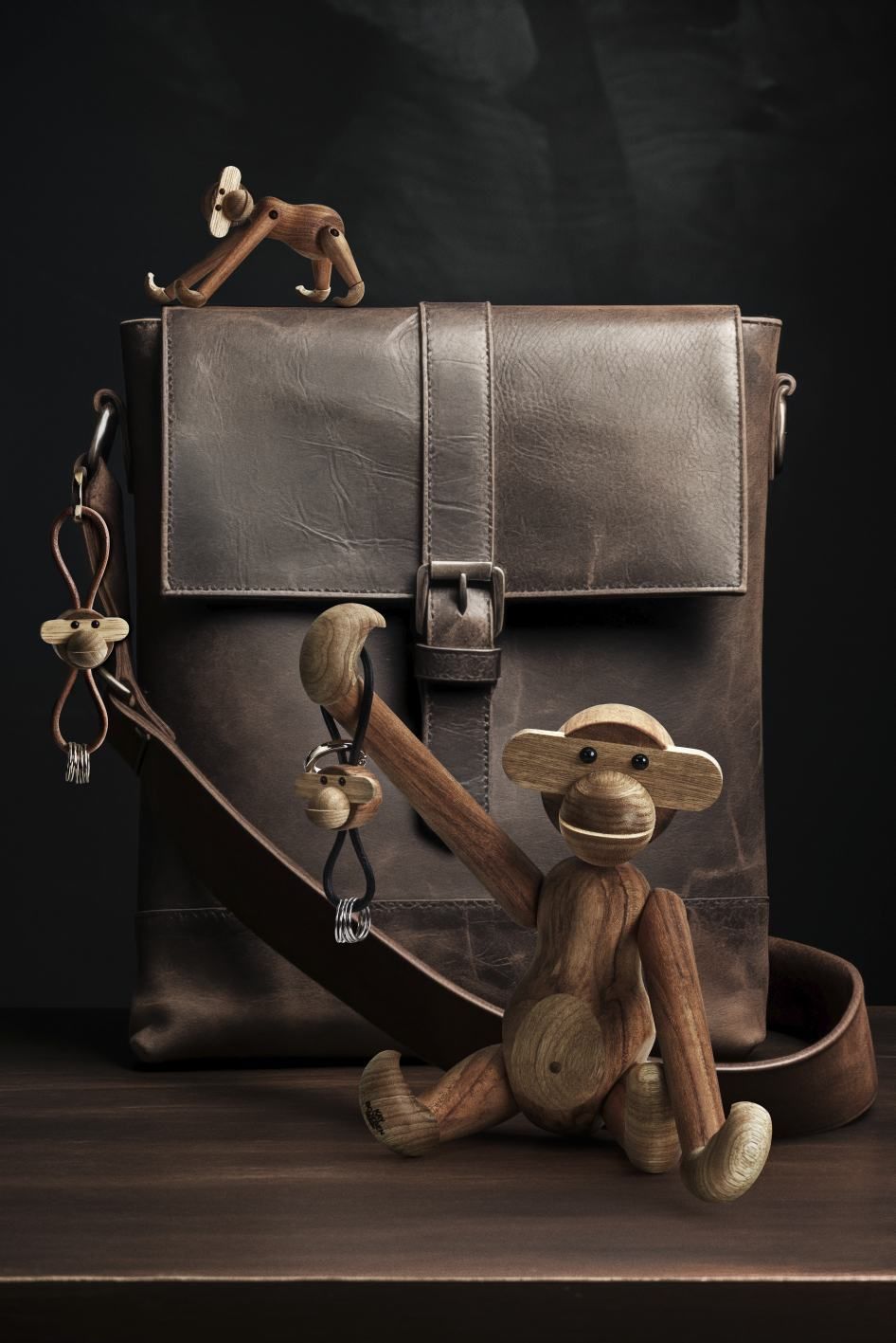 Kay Bojesen Affe aus Holz mit Schlüsselanhänger vor einer braunen Ledertasche.