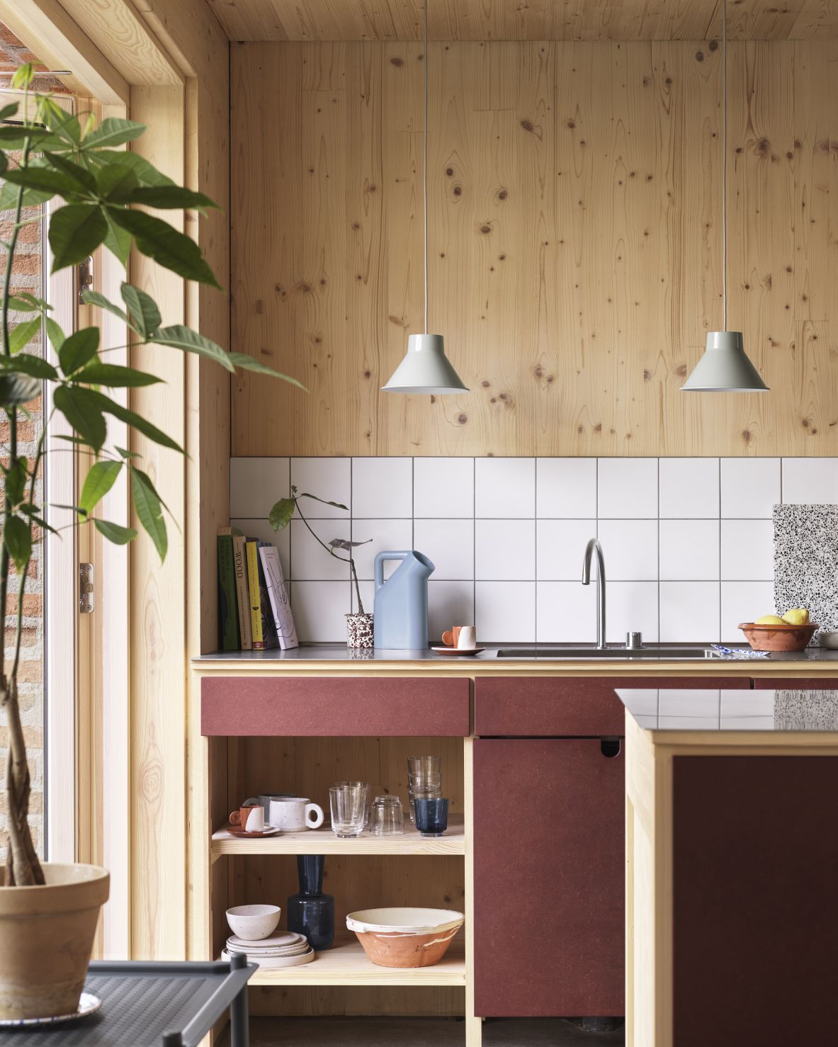 Helle Küche mit zwei grauen Muuto Top Pendelleuchten über einer Spüle, moderne Innenarchitektur.