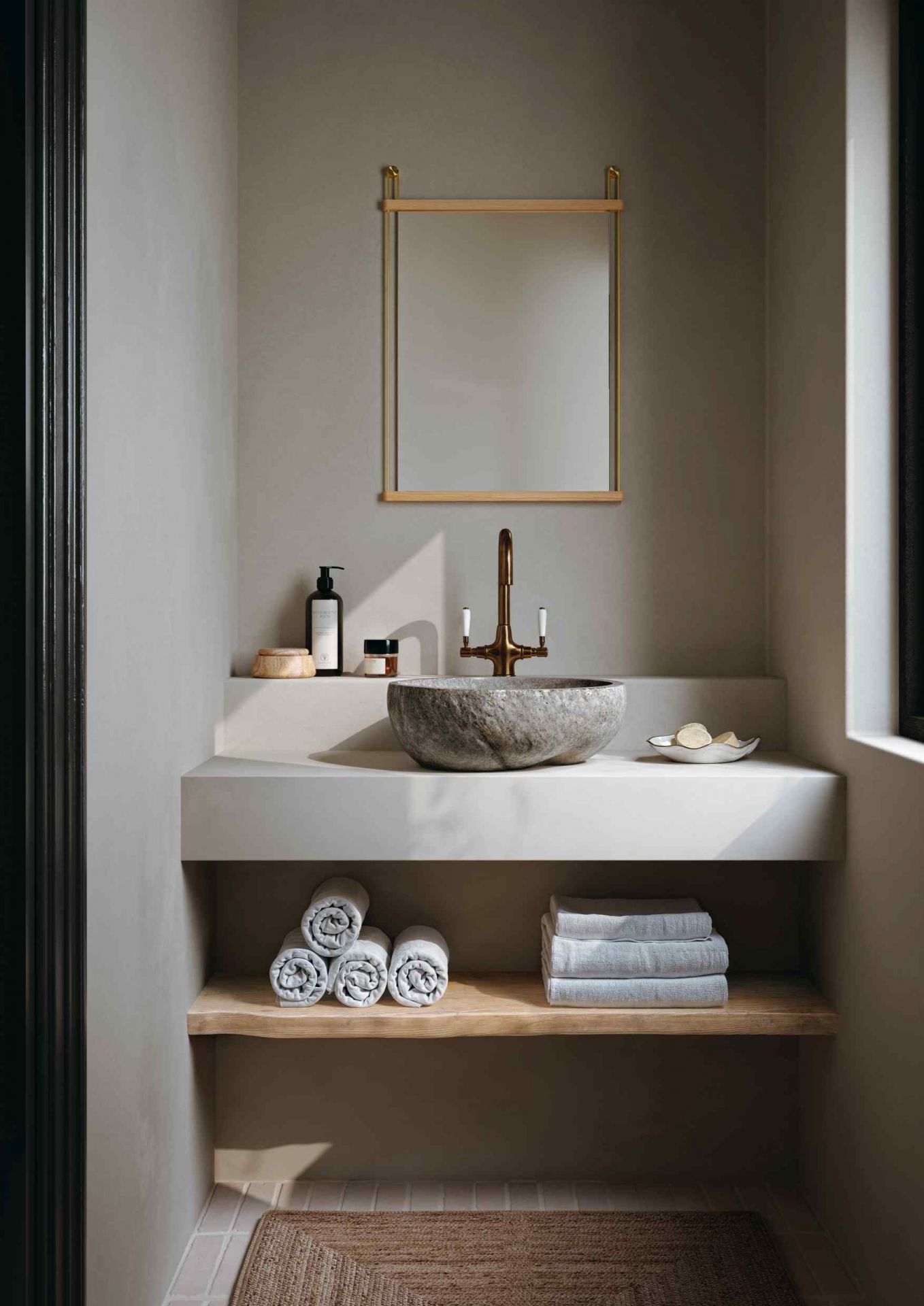 Badezimmer mit Waschtisch, Steinwaschbecken, Handtüchern und Woud Suspended Mirror mit Holzrahmen.