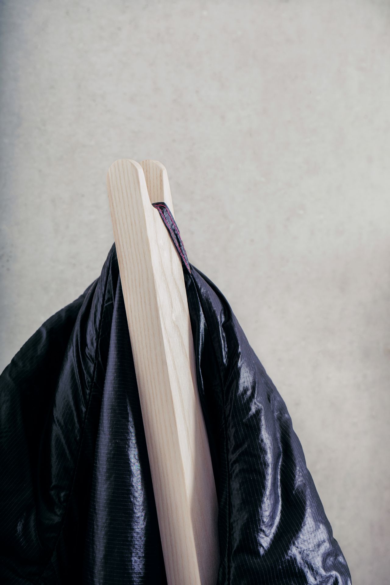 Nils Holger Moormann Pin Coat Garderobe mit Jacke aus leichtem, dunklem Stoff.