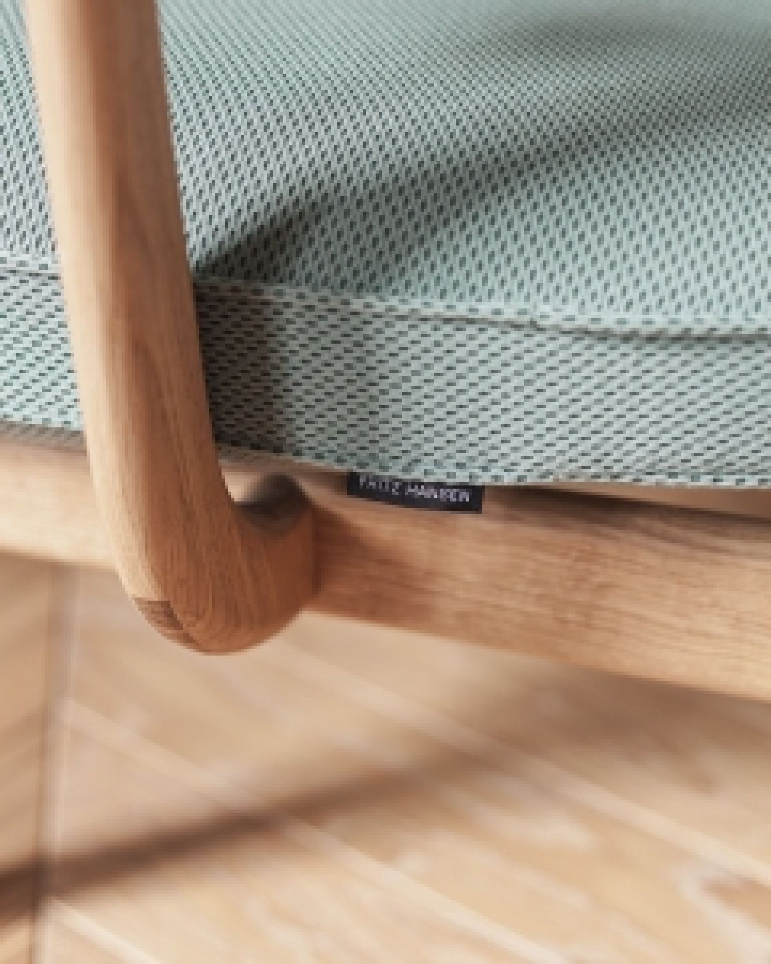 Detailaufnahme: Fritz Hansen Fred Loungesessel mit hellblauem Bezug und Holzrahmen, modernes Designmöbel.