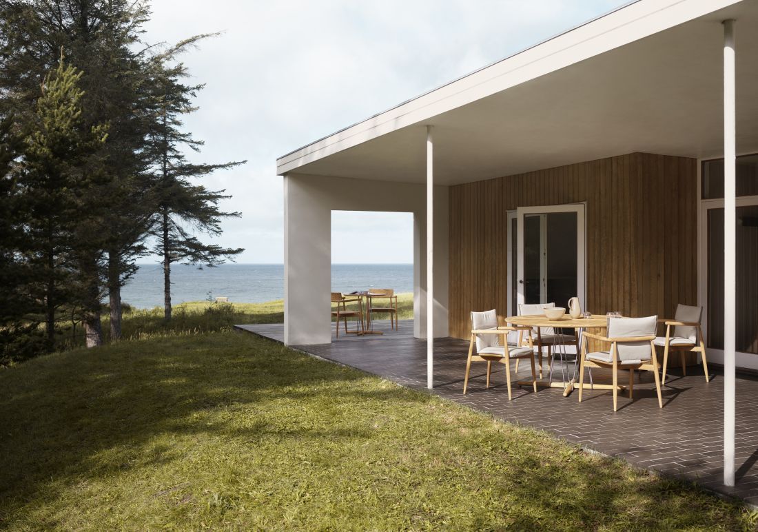 E022 Embrace Outdoor Tisch von Carl Hansen & Søn auf einer Terrasse mit Meerblick.