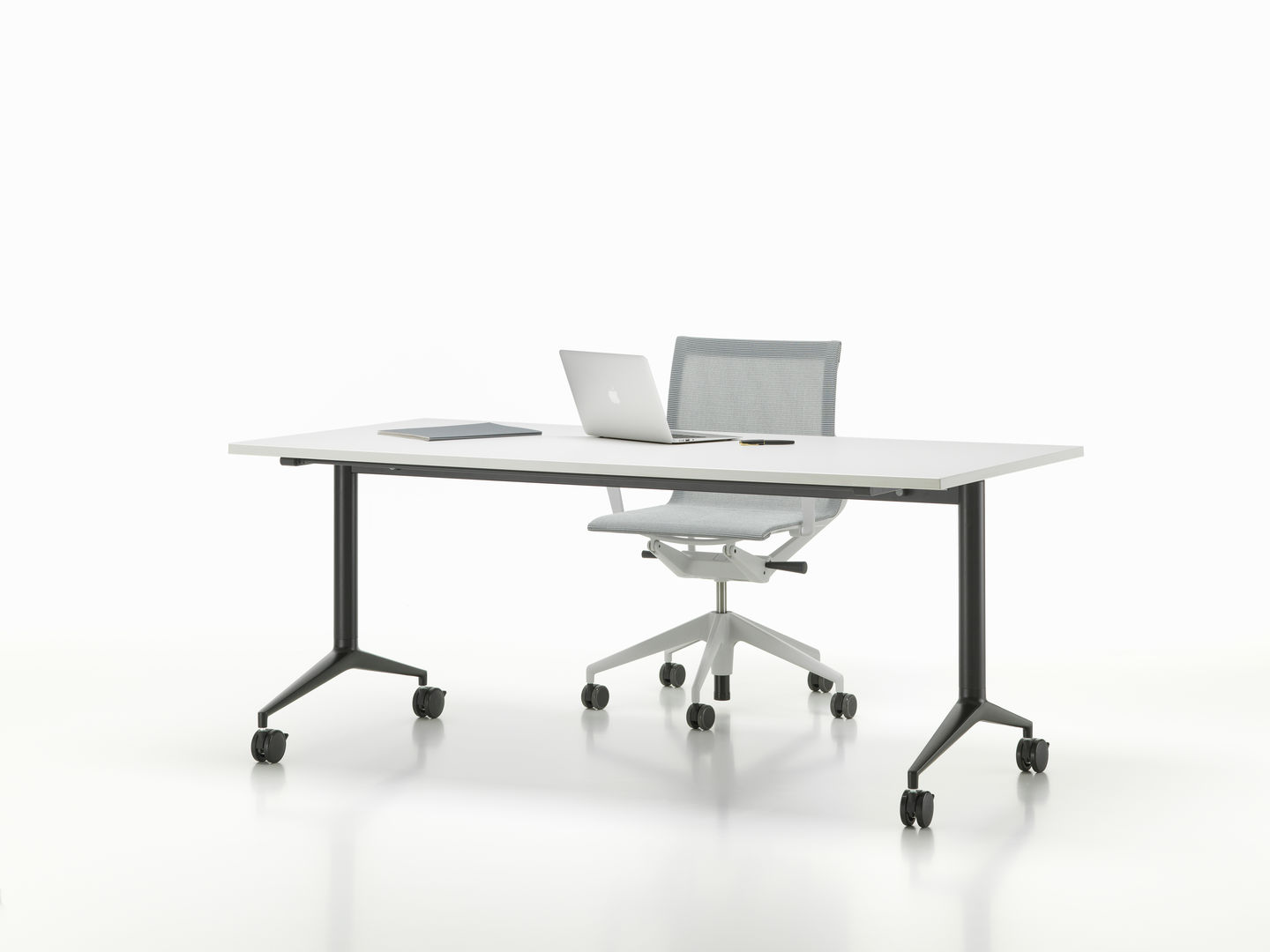 Vitra MedaMorph Klapptisch mit Laptop, Tablet und Bürostuhl vor weißem Hintergrund.