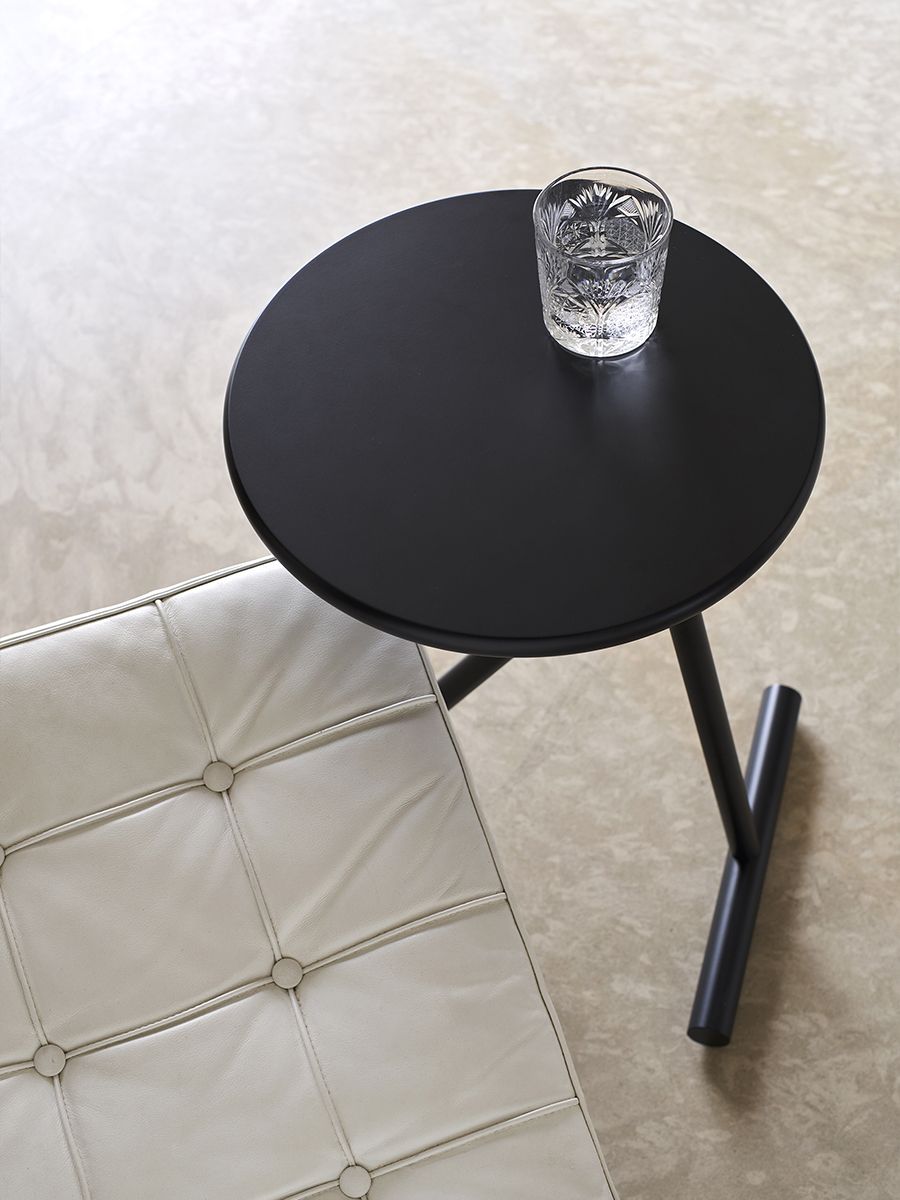 Schwarzer Koji Beistelltisch von Opinion Ciatti mit Glas Wasser, höhenverstellbarer Couchtisch neben Ledersessel.