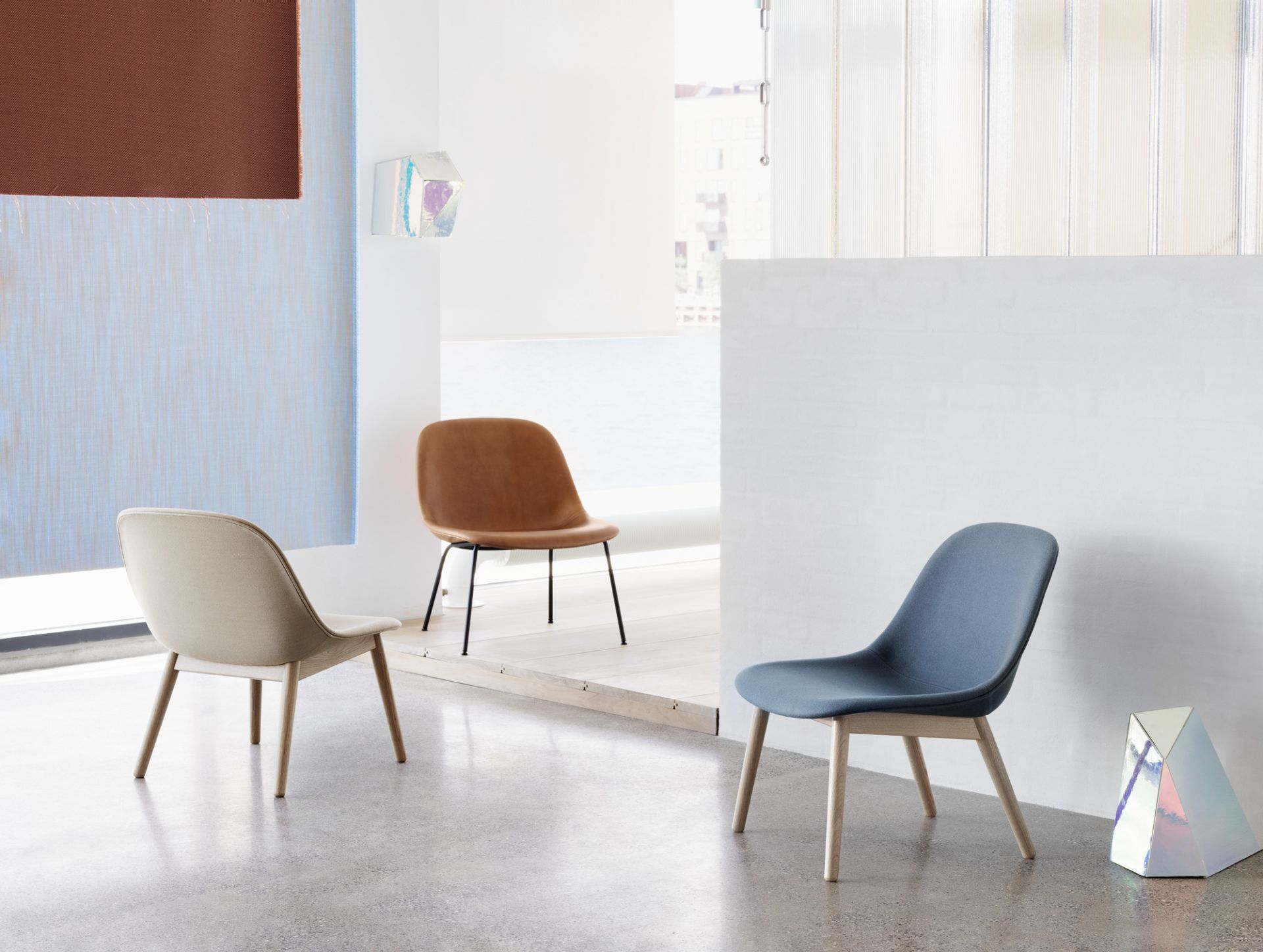 Drei Fiber Lounge Chairs von Muuto in Beige, Braun und Blau mit Holz- und Metallgestell.