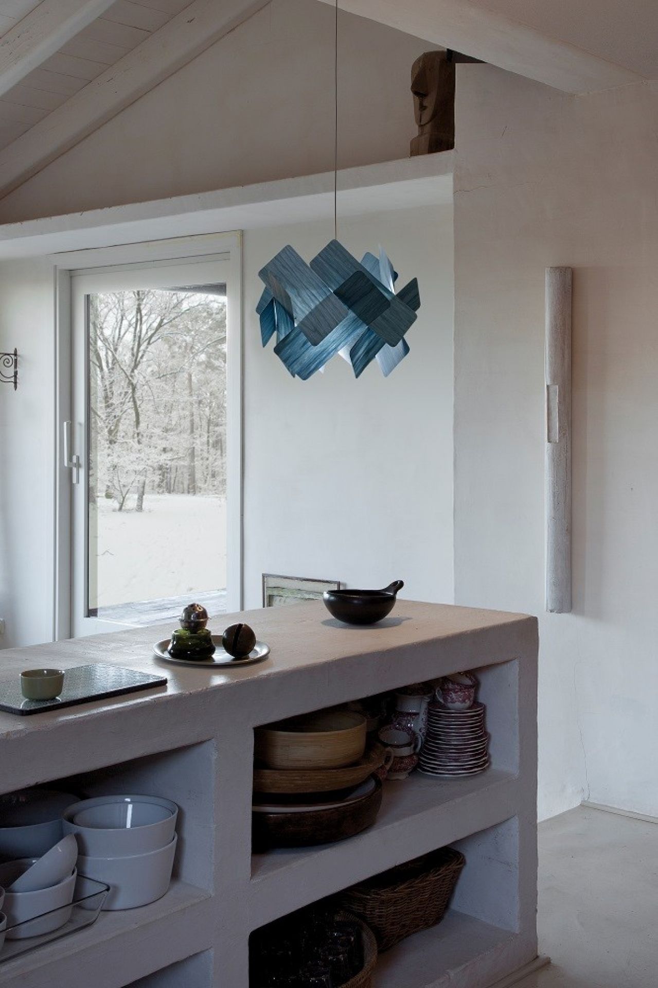 Blaue Escape LED Pendelleuchte von LZF Lamps über Küchentheke mit Geschirr und Blick nach draußen.