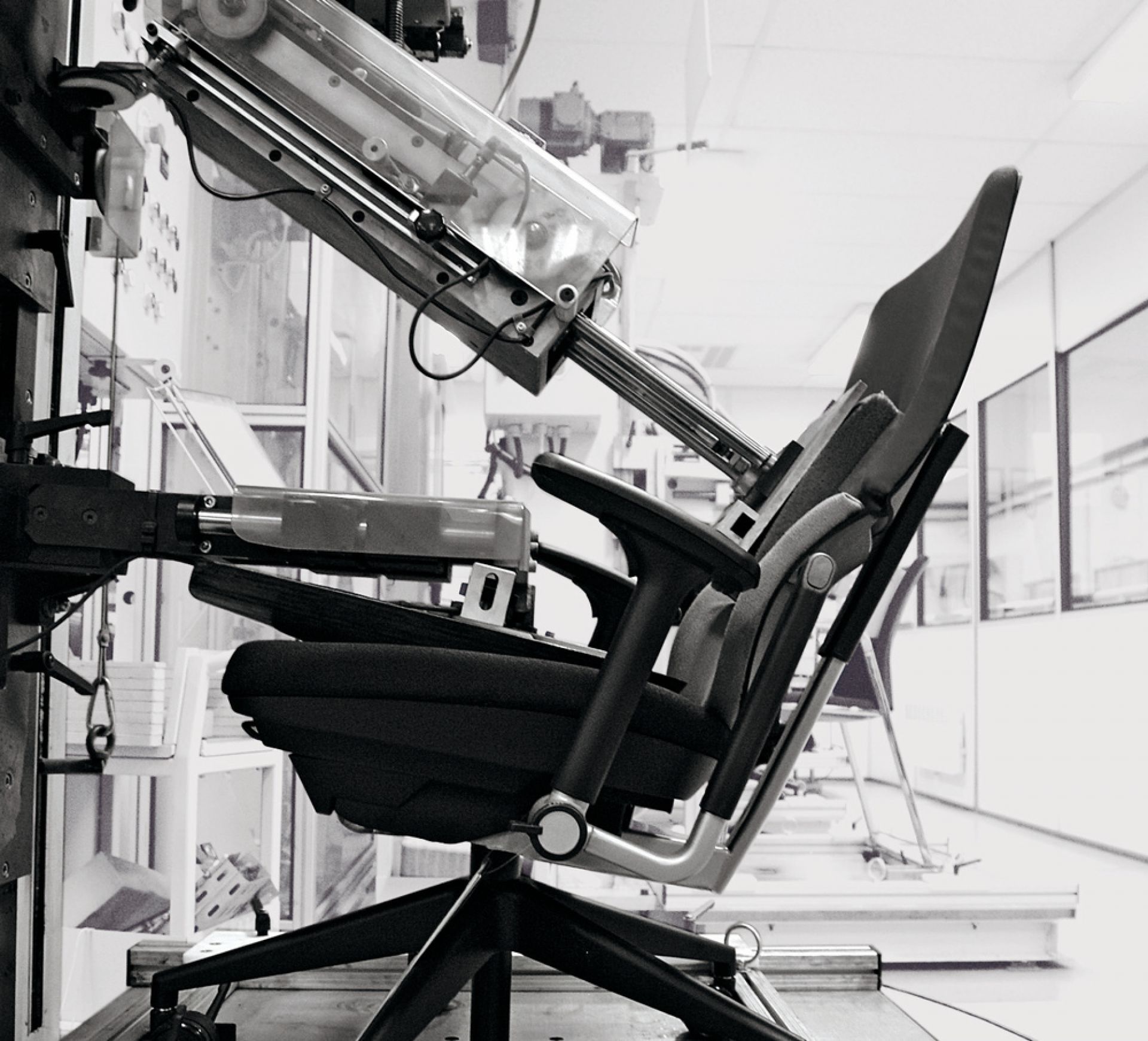 Schwarz-Weiß-Foto eines Please Drehstuhls von Steelcase im Testlabor, geprüft mit einer Maschine.