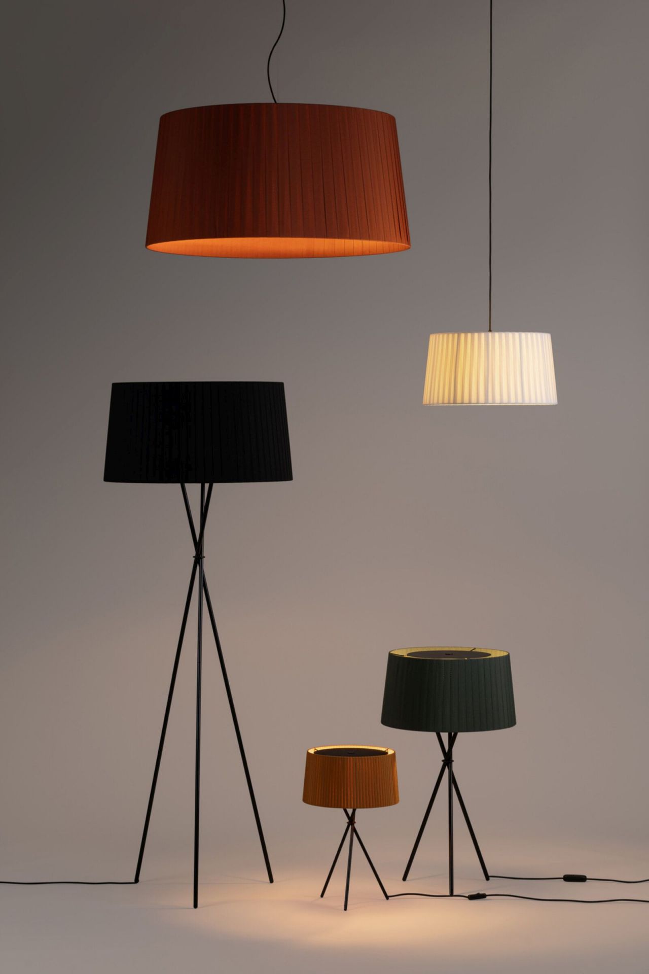 Verschiedene Santa & Cole Lampen: Pendelleuchte, Stehlampe und Tischleuchte mit plissierten Lampenschirmen.