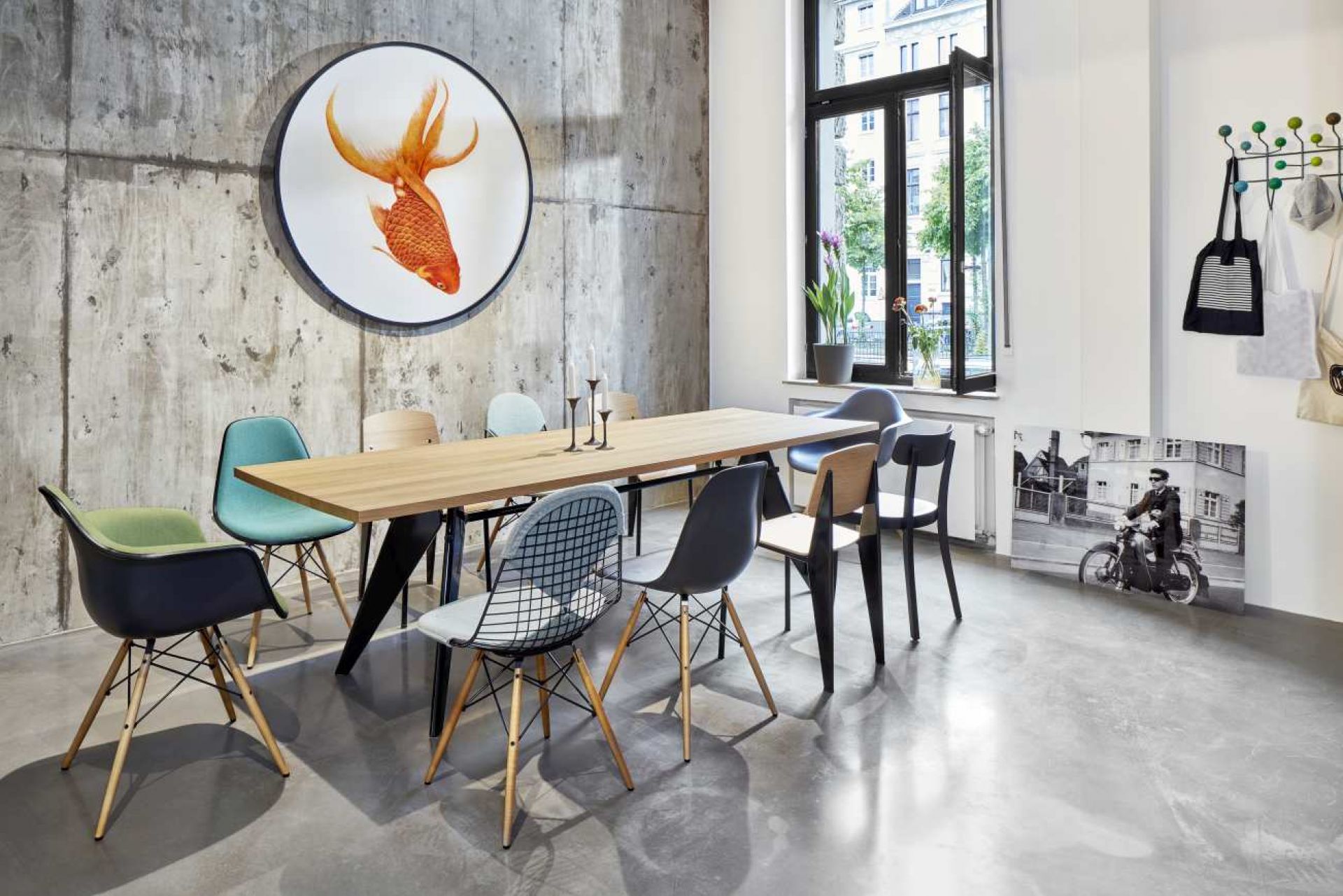 Vitra EM Table Holztisch mit Stühlen in modernem Esszimmer mit Betonwand und Fischbild.