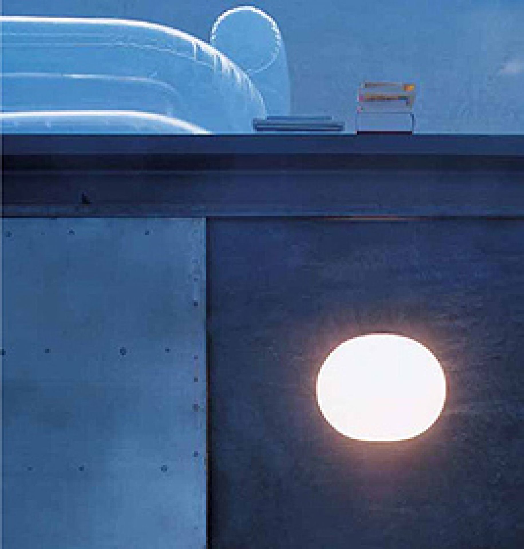 Weiße, runde Glo-Ball Wandleuchte von Flos an dunkler Wand. Moderne Wandlampe für stimmungsvolle Beleuchtung.