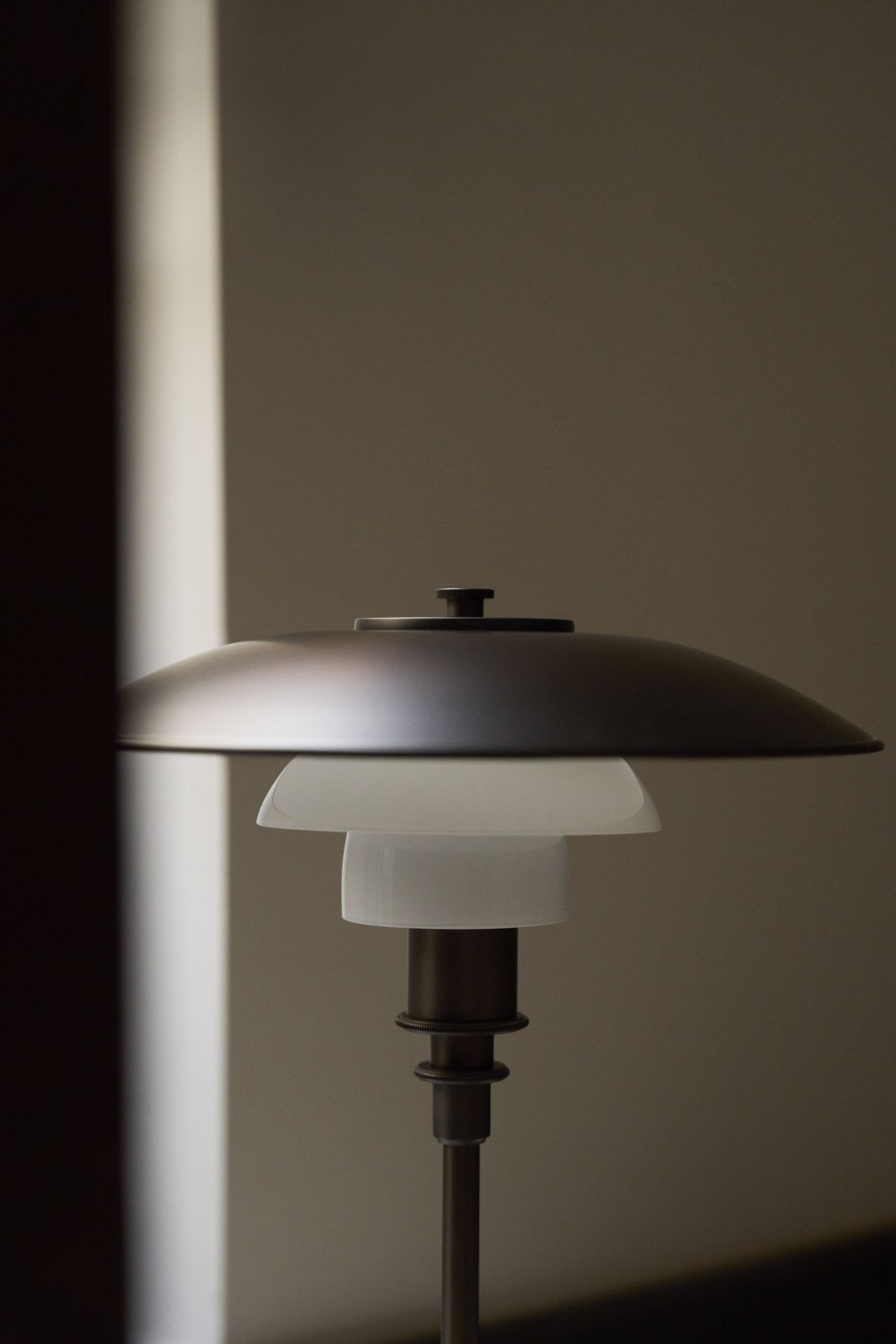 Nahaufnahme der Louis Poulsen PH 3/2 Tischleuchte aus Messing und Opalglas, modernes Design.