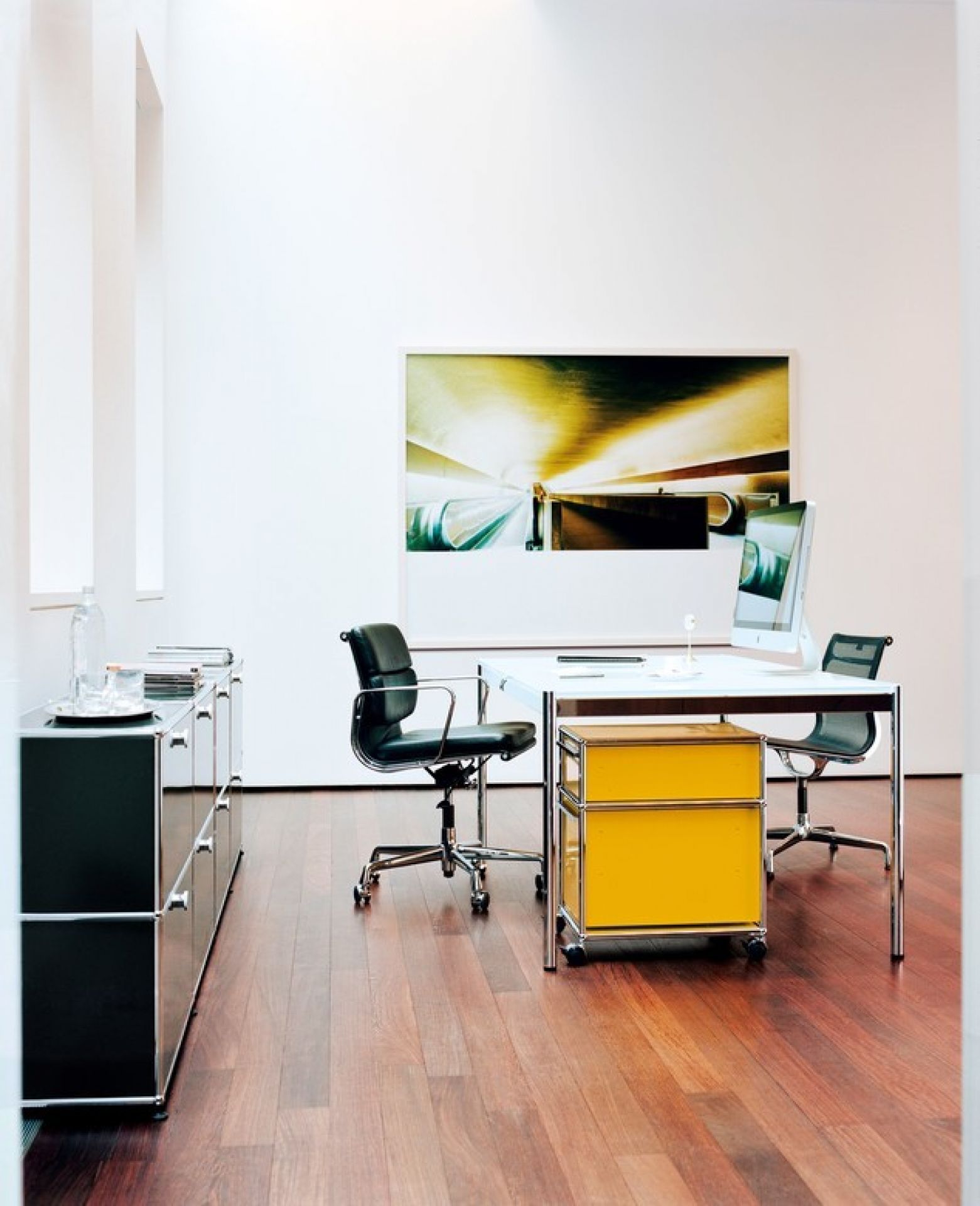 Büro mit USM Haller Rollcontainer in Enzianblau unter Schreibtisch, Stauraum und Büromöbel.