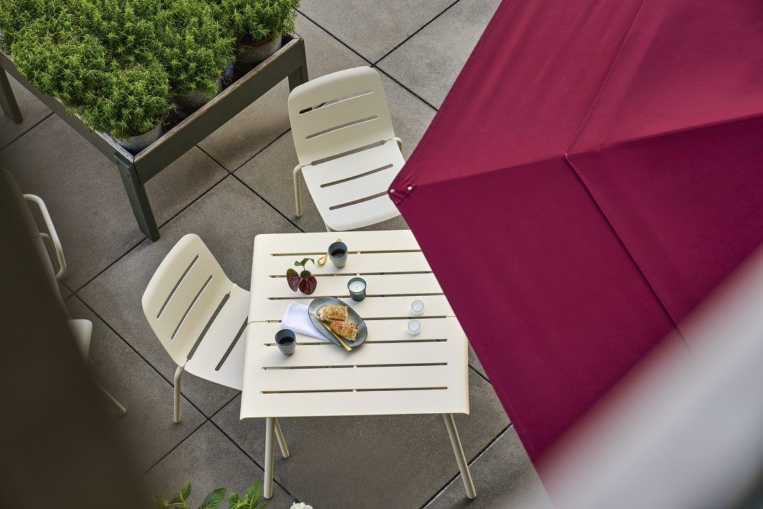 Weishäupl Vapio Stuhl und Tisch für den Außenbereich, modernes Design mit burgunderrotem Sonnenschirm.