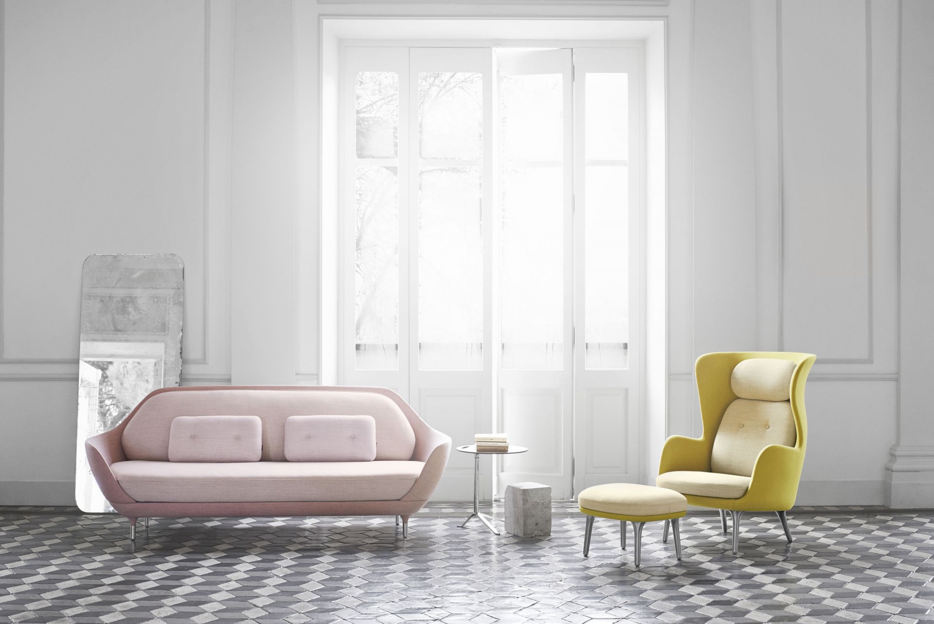 Heller Raum mit Ro Sessel von Fritz Hansen in Gelb und rosa Sofa mit Kissen.
