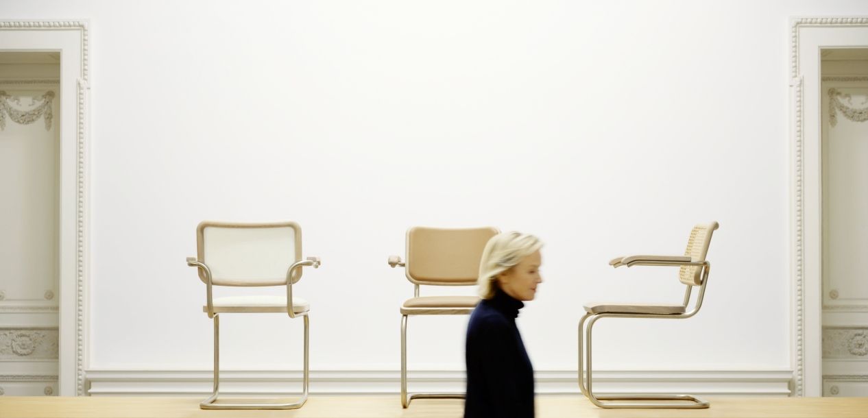 Drei JS. Thonet Freischwinger S 64 V Stühle in verschiedenen Ausführungen vor weißer Wand.