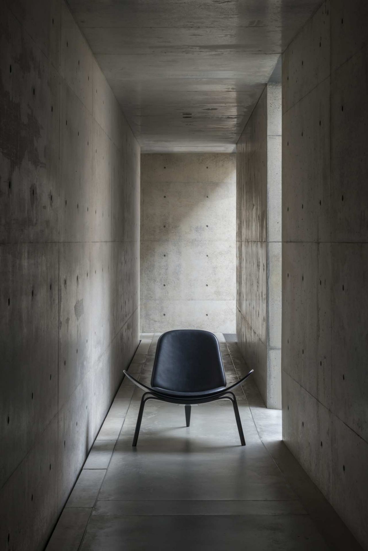 Schwarzer CH07 Shell Chair Stuhl von Carl Hansen & Søn in einem modernen Betonraum.