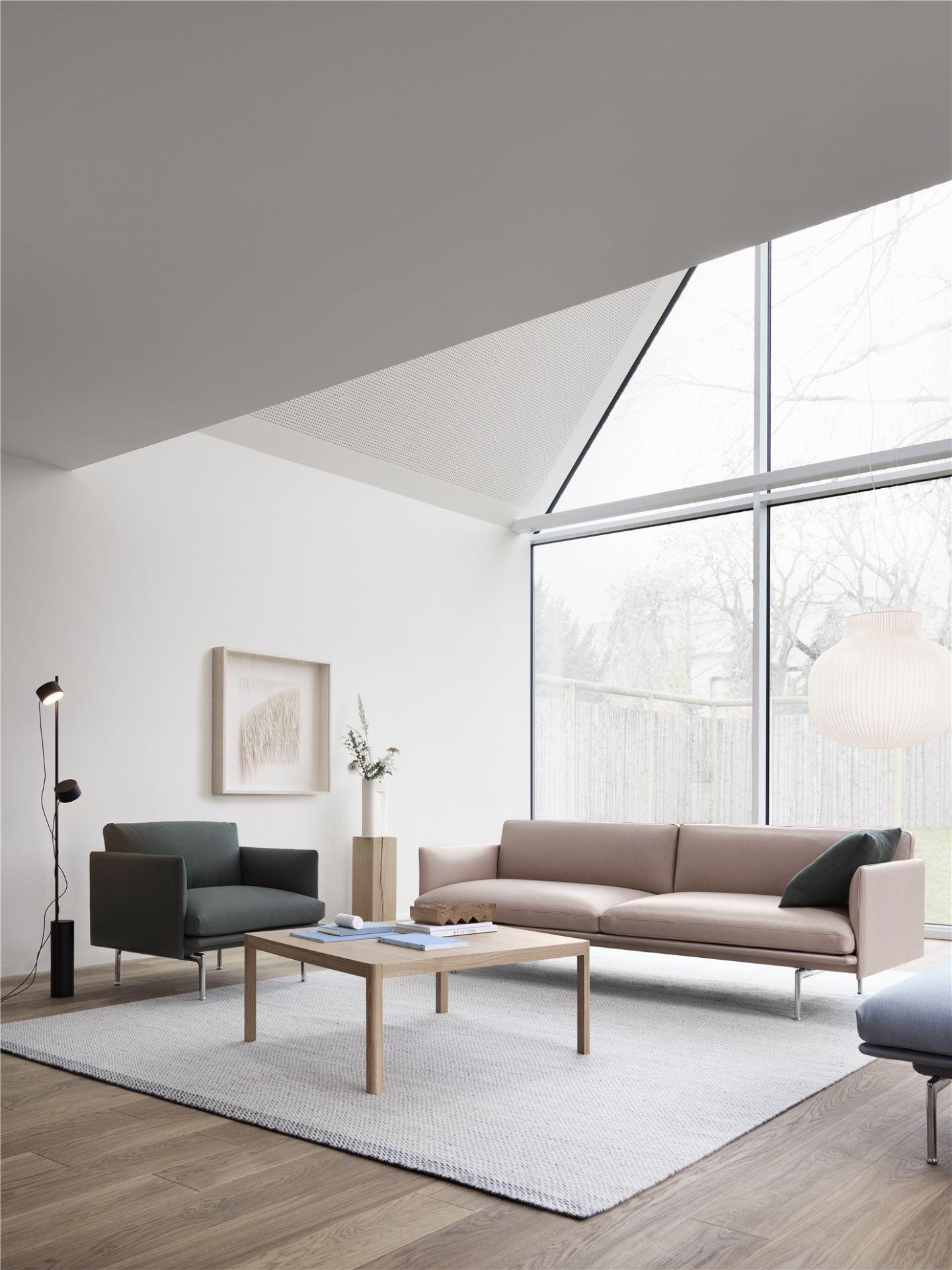 Wohnzimmer mit Muuto Outline Chair Sessel in Grün, Sofa, Tisch und großem Fenster.