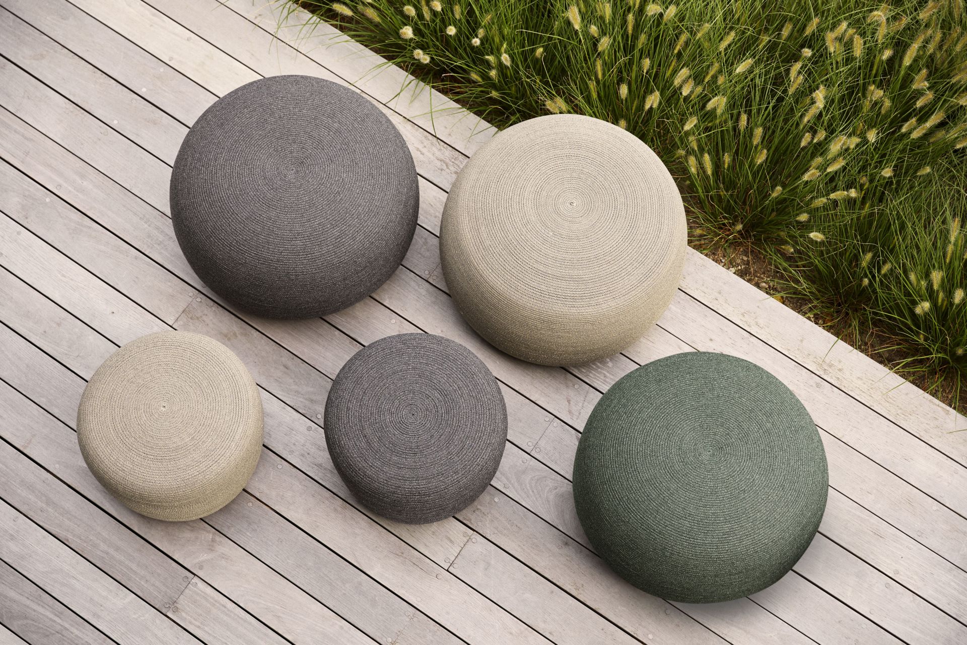 Circle Hocker von Cane-Line in verschiedenen Farben auf einer Holzterrasse, Gartenmöbel für den Außenbereich.