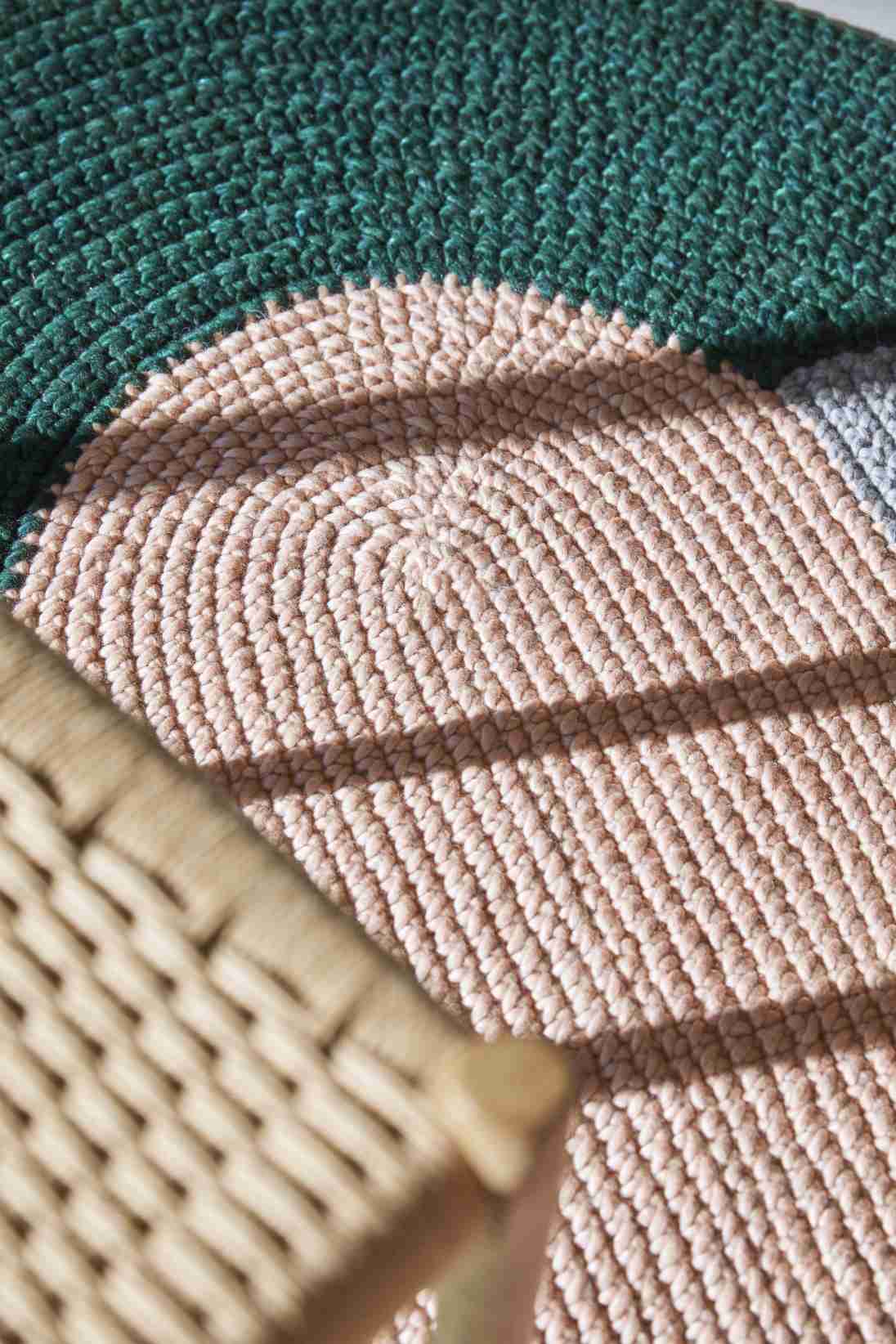 Nahaufnahme des The Crochet Collection Teppichs in Grün, Rosa und Grau, gehäkeltes Design.