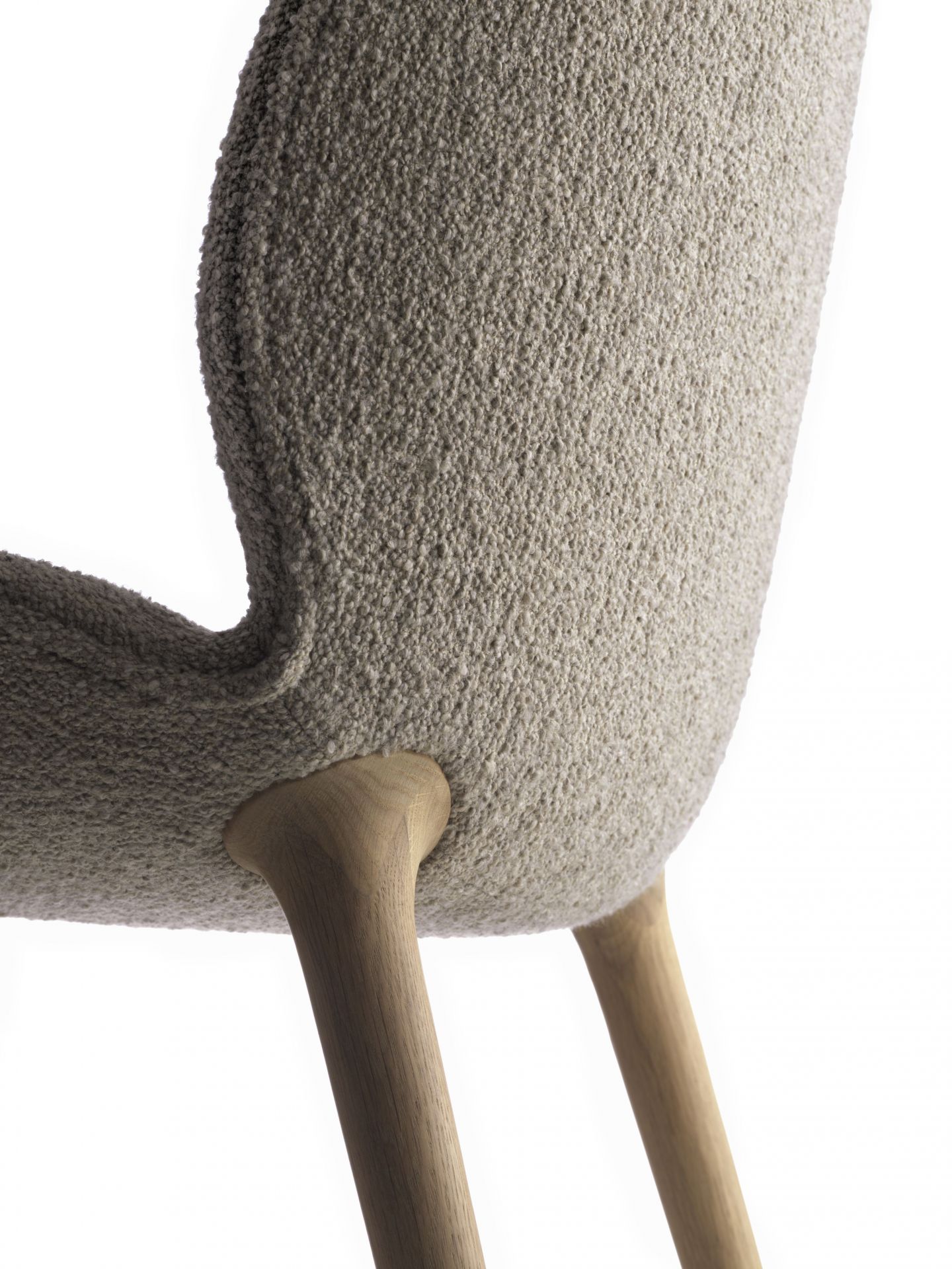 Detailaufnahme des Lodge Stuhls: Strukturierter Stoffbezug und helle Holzbeine, modernes Design für Wohnzimmer.