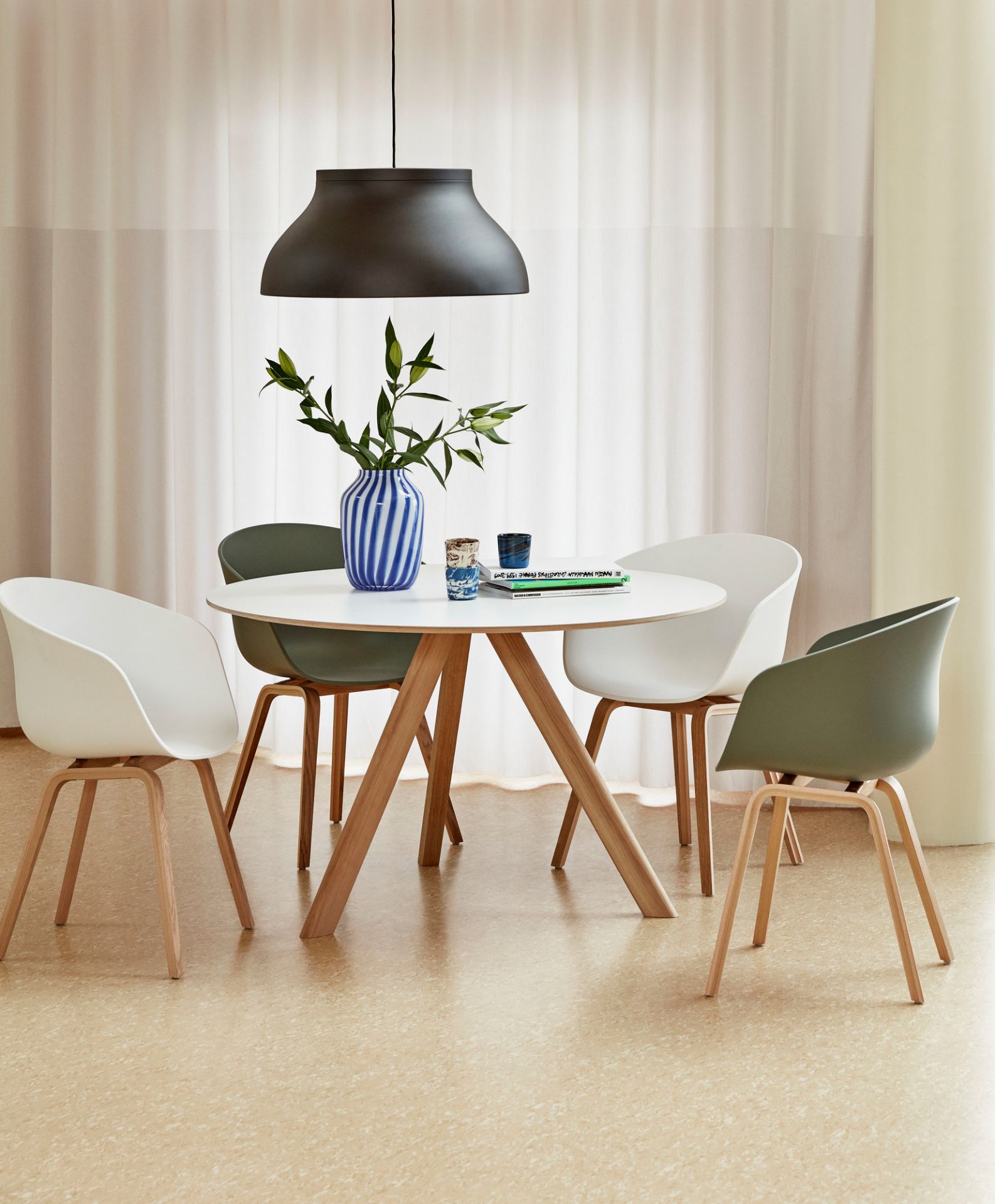 Heller Raum mit Copenhague Table CPH 20 Tisch rund von Hay, umgeben von vier Stühlen.